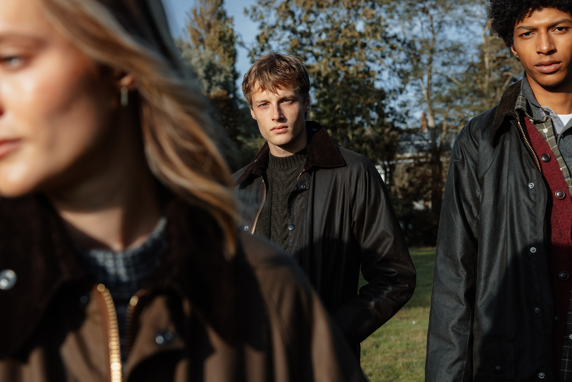 1 Women and 2 men in the background wearing Barbour wax jackets in the country side.