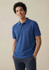 Man wearing a blue polo shirt with a logo on a beige background