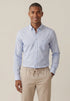 Man wearing a light blue checkered shirt and beige pants against a beige background