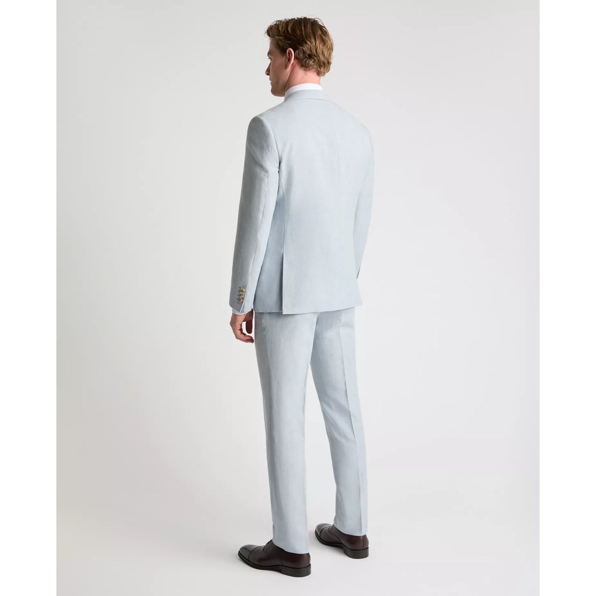 Man wearing a sky blue suit standing against a white background