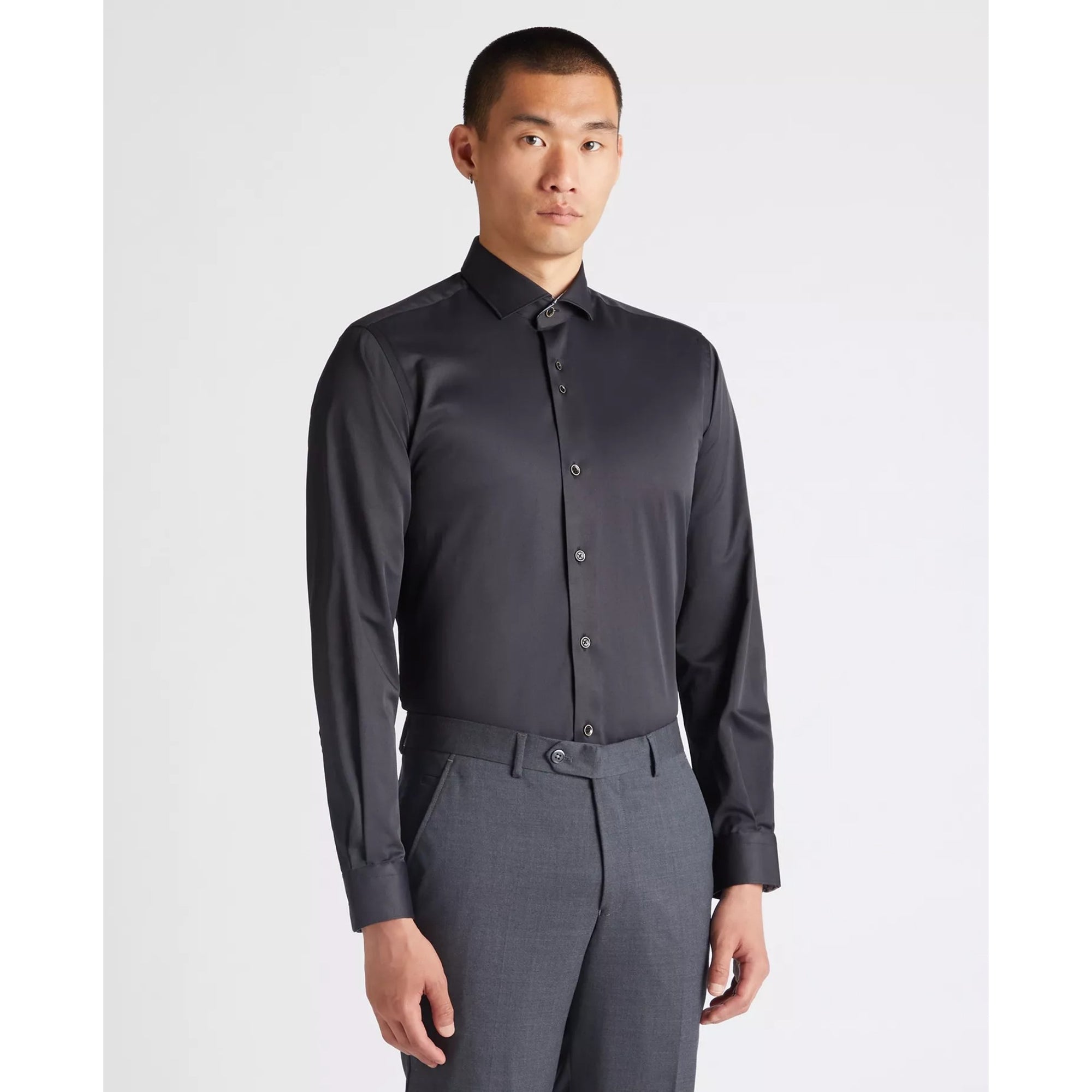 Man wearing a black dress shirt and gray pants on a white background