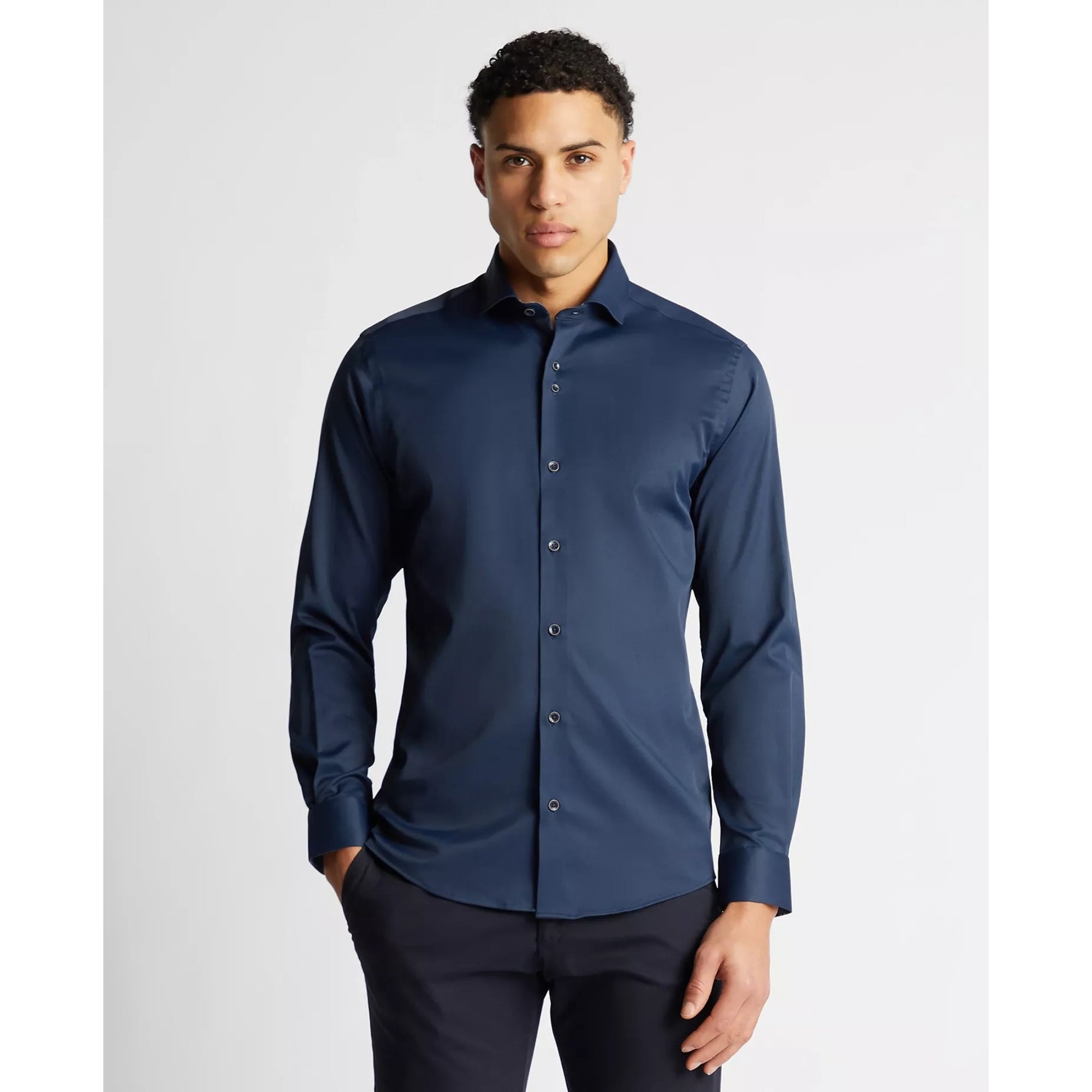 Man wearing a navy blue dress shirt against a light gray background