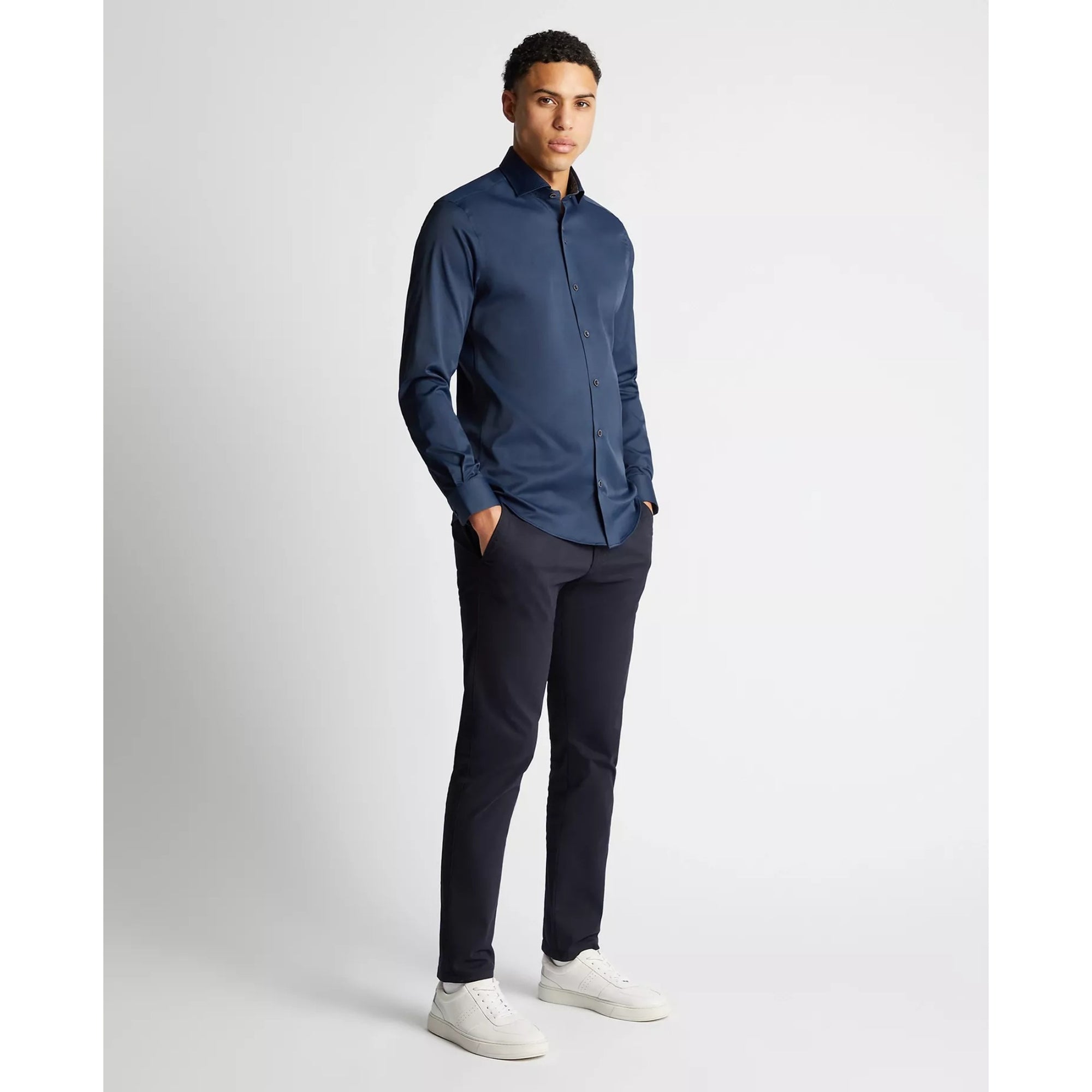 Man wearing a blue shirt and black pants on a white background