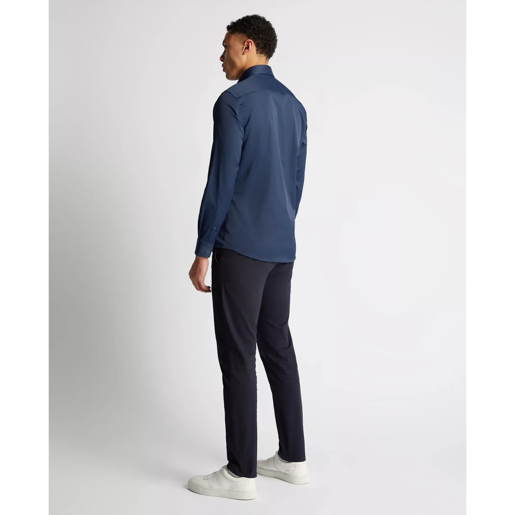 Man wearing a blue shirt and black pants on a white background