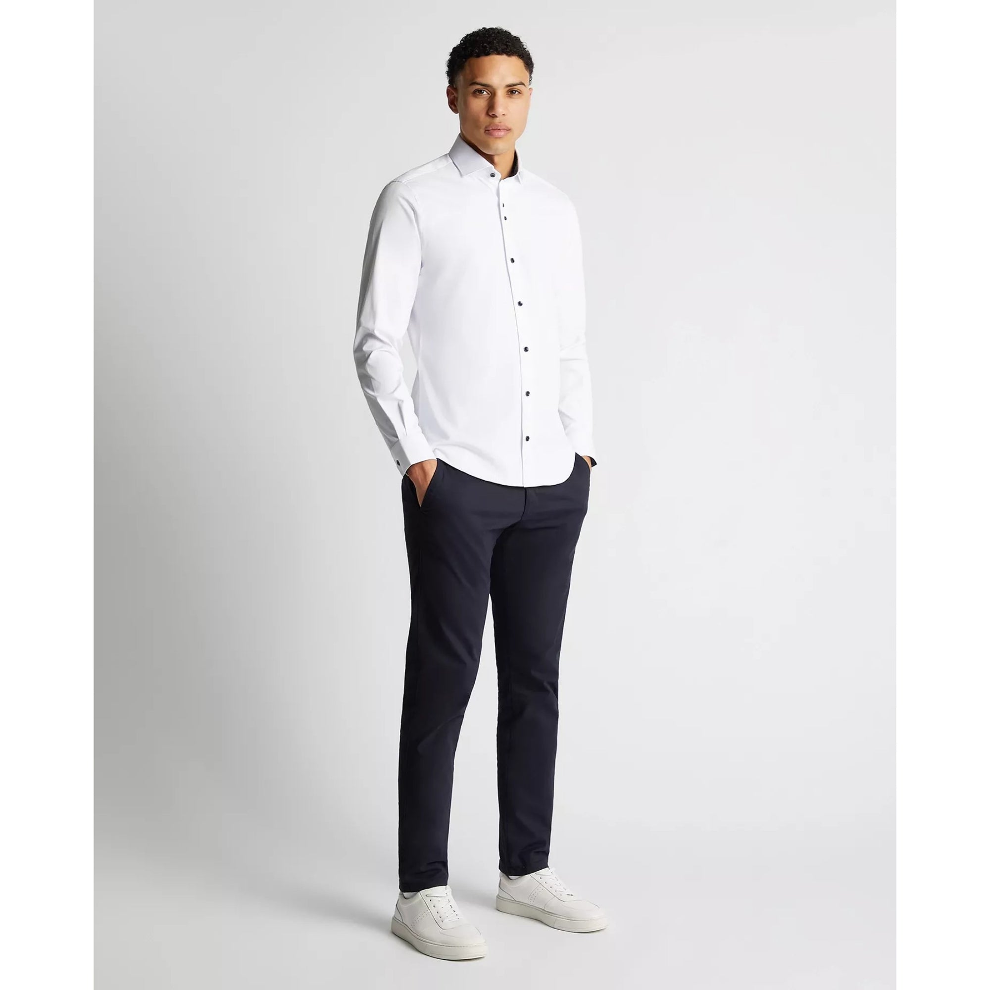 Man wearing a white dress shirt and black pants on a light gray background