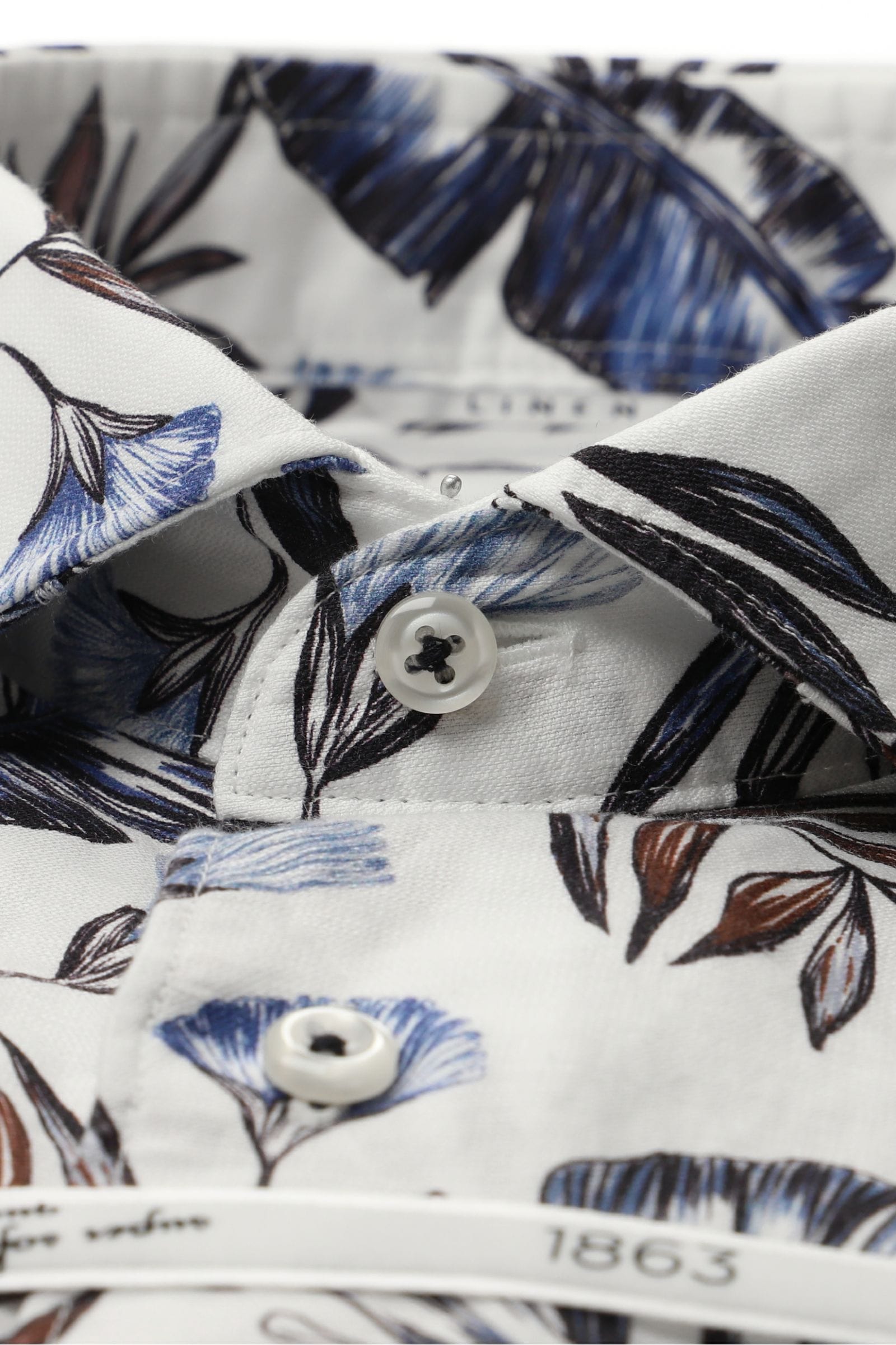 Close-up of a shirt with blue and brown floral pattern on a white background
