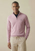 Man wearing a pink half-zip sweater and beige pants against a beige background