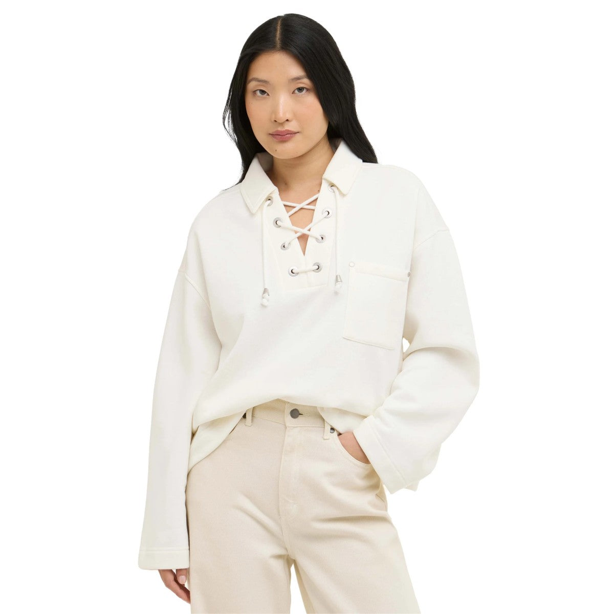 Woman wearing a white lace-up shirt and beige pants on a white background