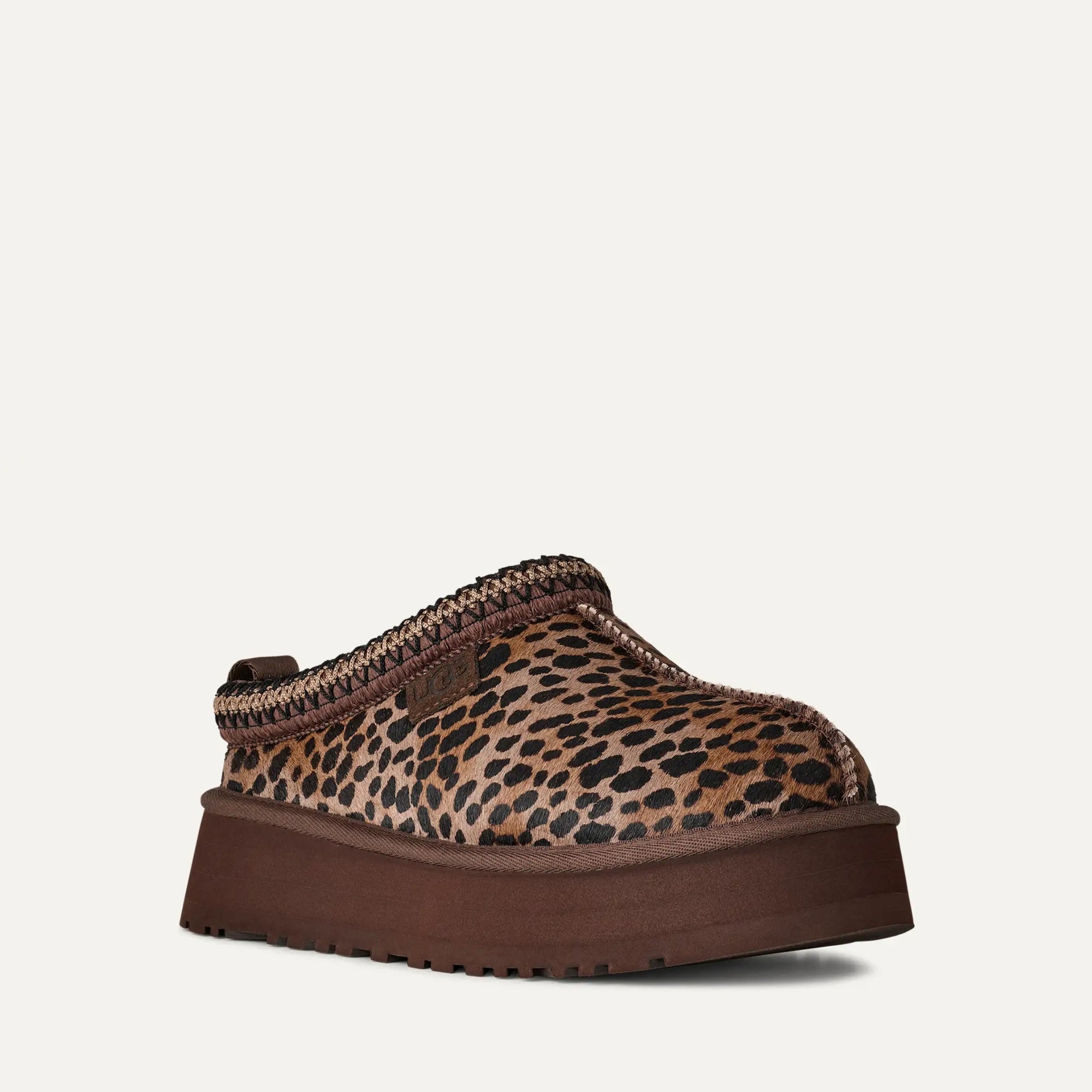 Leopard print slipper with brown sole on a light gray background