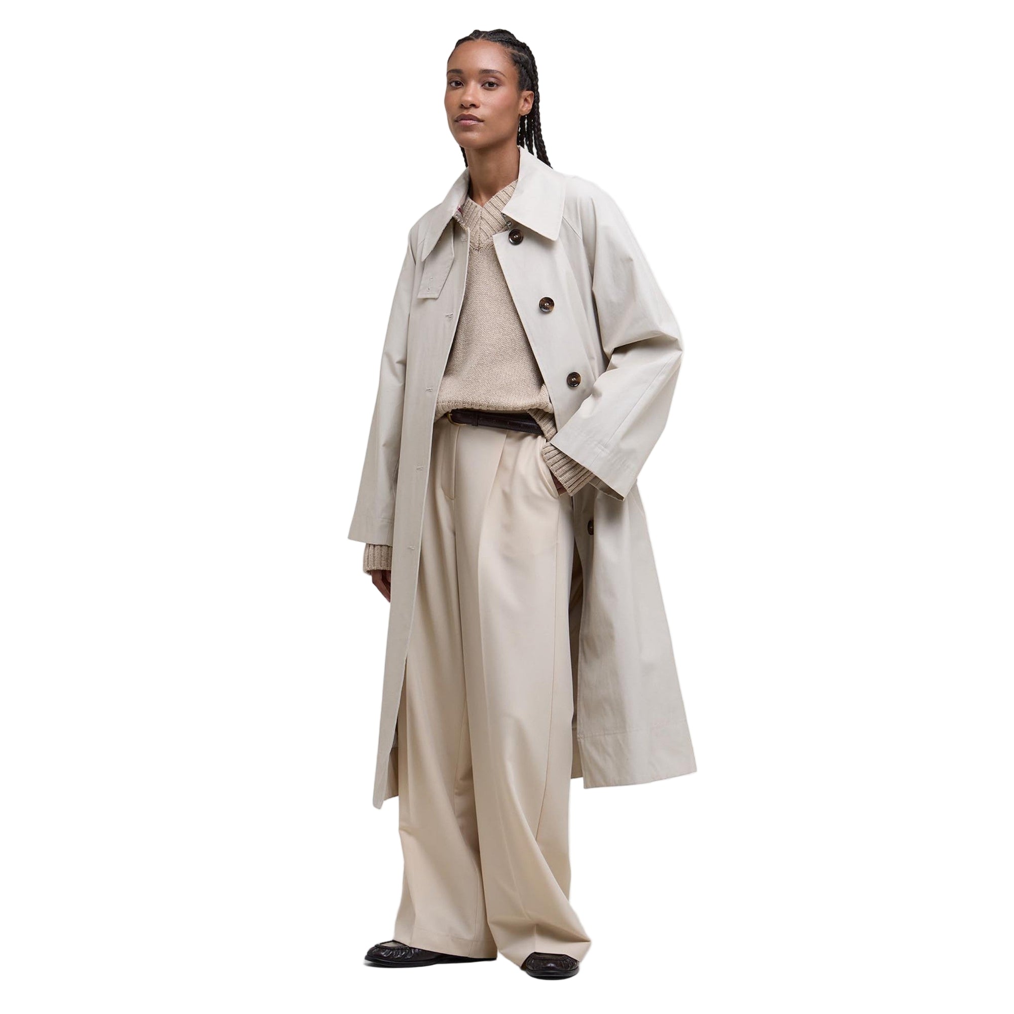 Person wearing a beige trench coat and pants on a white background