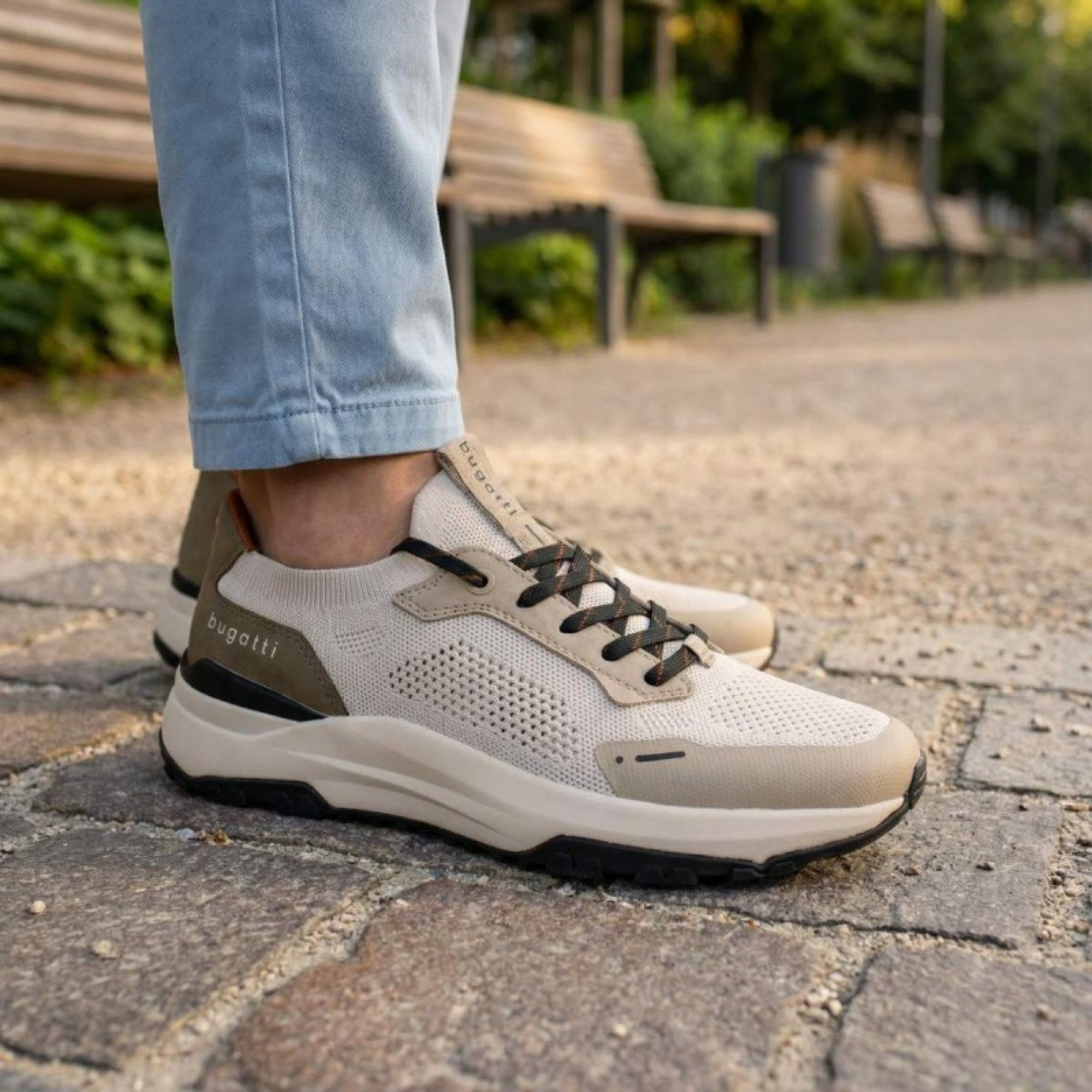 Person wearing beige and gray sneakers on a paved path with blurred background