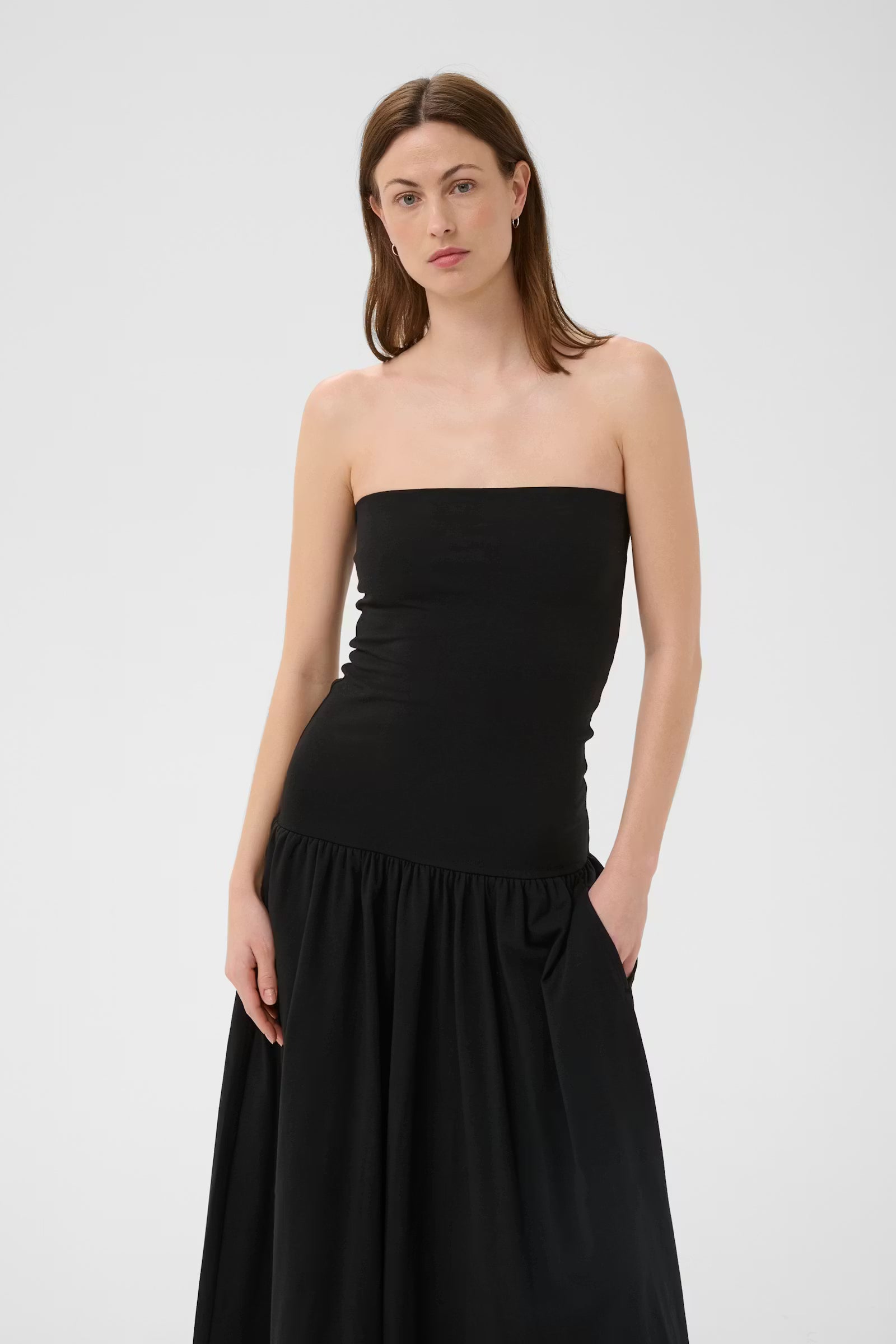 Woman wearing a black strapless dress on a white background
