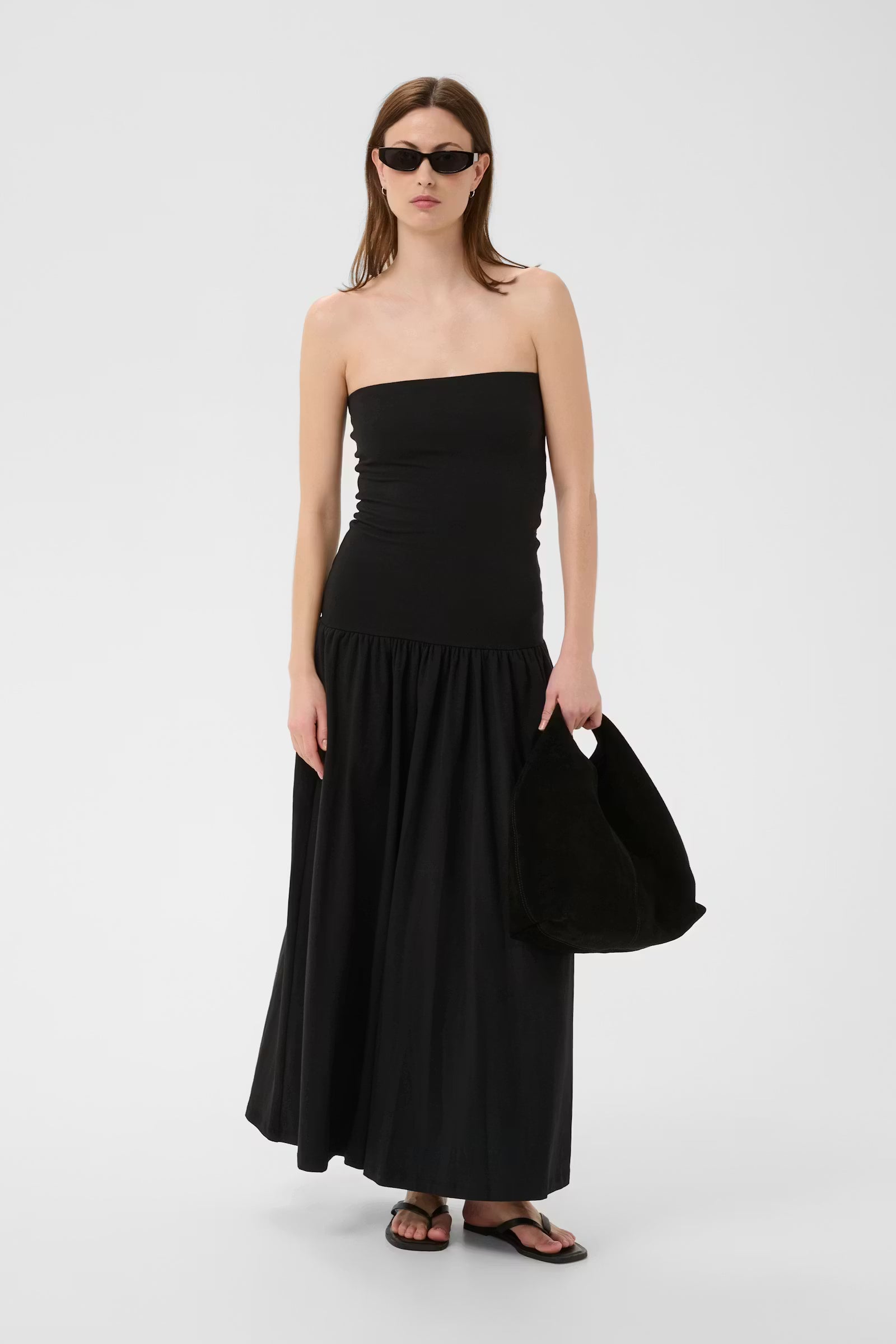 Woman wearing a black strapless dress on a white background