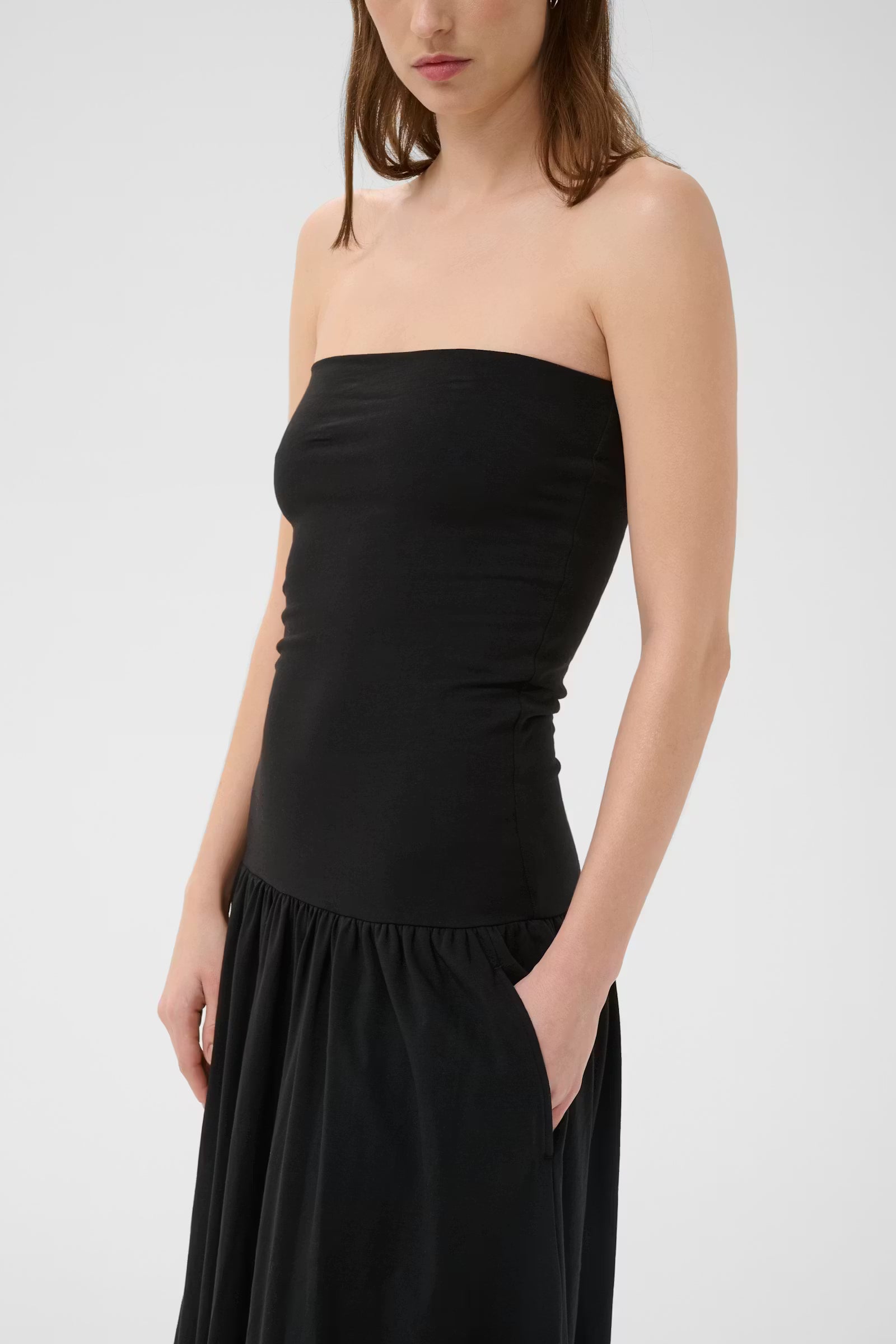 Woman wearing a black strapless dress against a white background