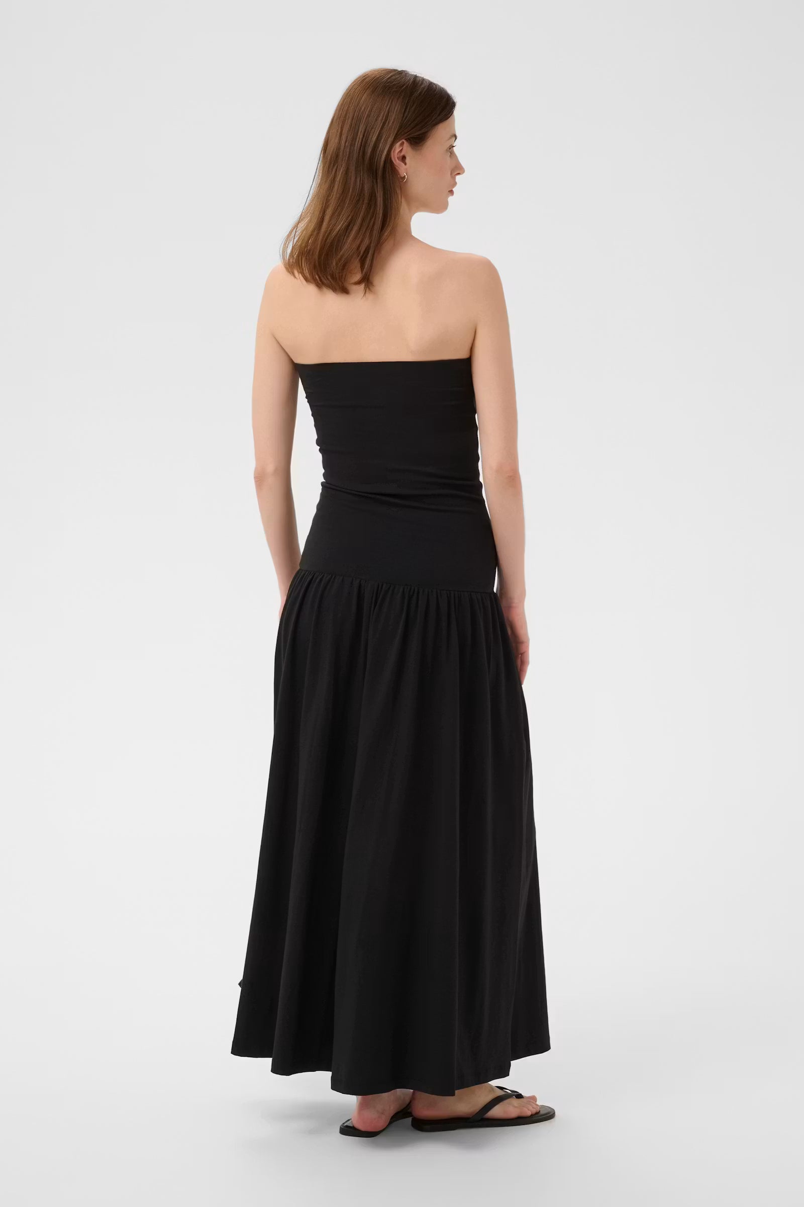 Woman wearing a black strapless dress on a white background