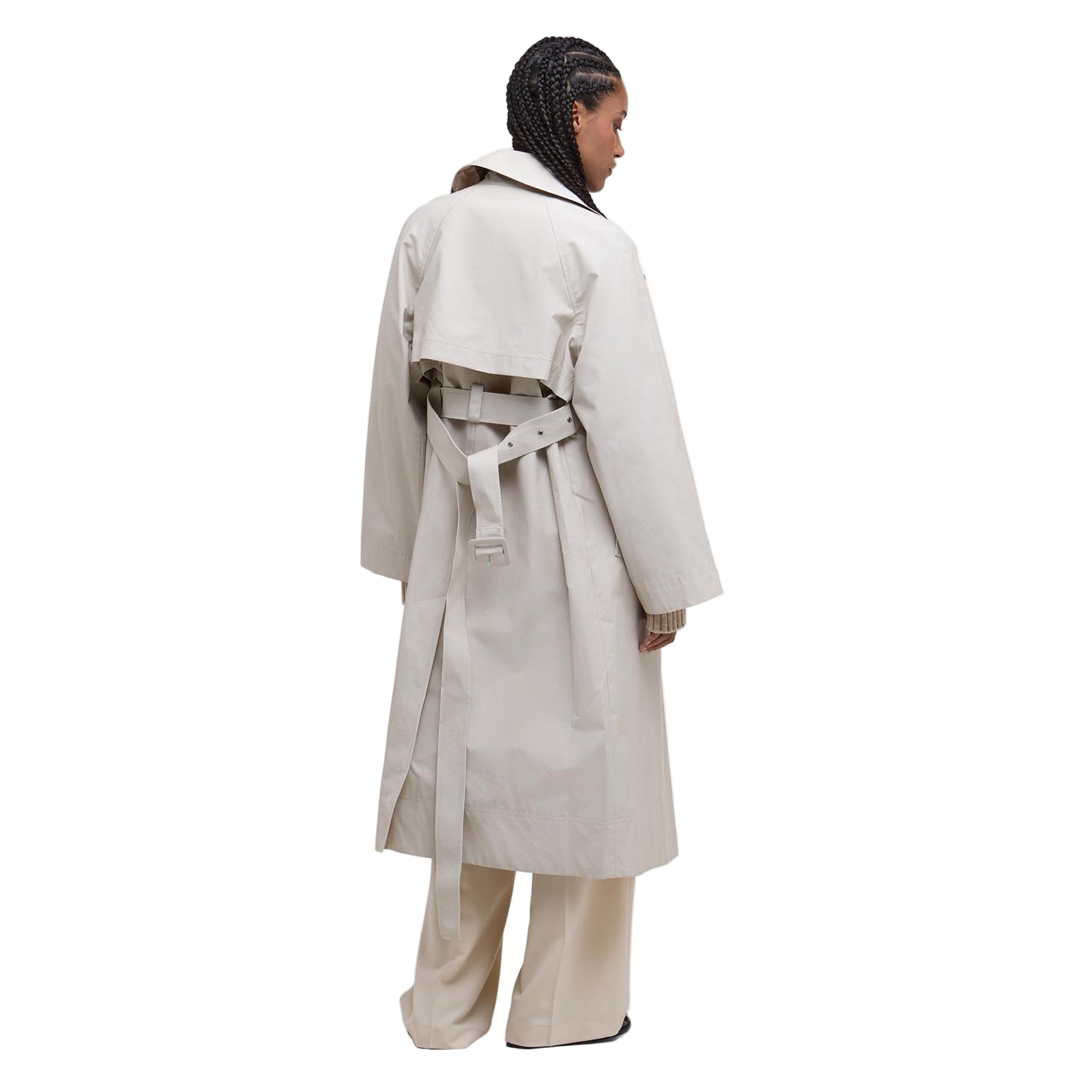 Person wearing a beige trench coat on a white background