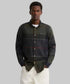 A man wearing a Barbour dark green and navy plaid button-down shirt with a chest pocket, paired with white pants, against a plain white background.