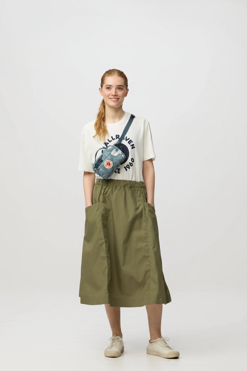 Person wearing a graphic t-shirt and green skirt on a white background