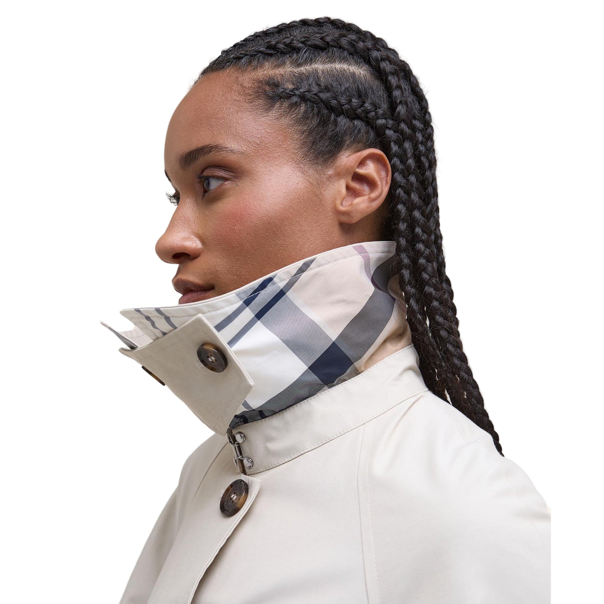 Woman wearing a beige coat with a plaid scarf, on a plain background