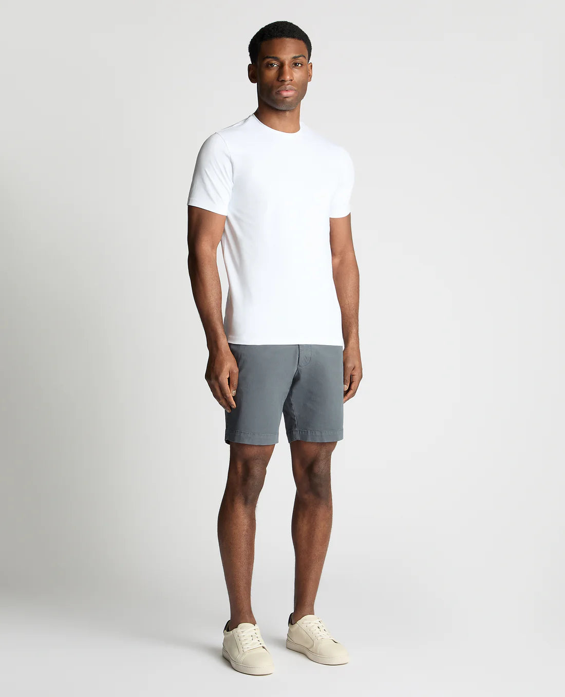 Man wearing a white t-shirt and gray shorts on a plain background