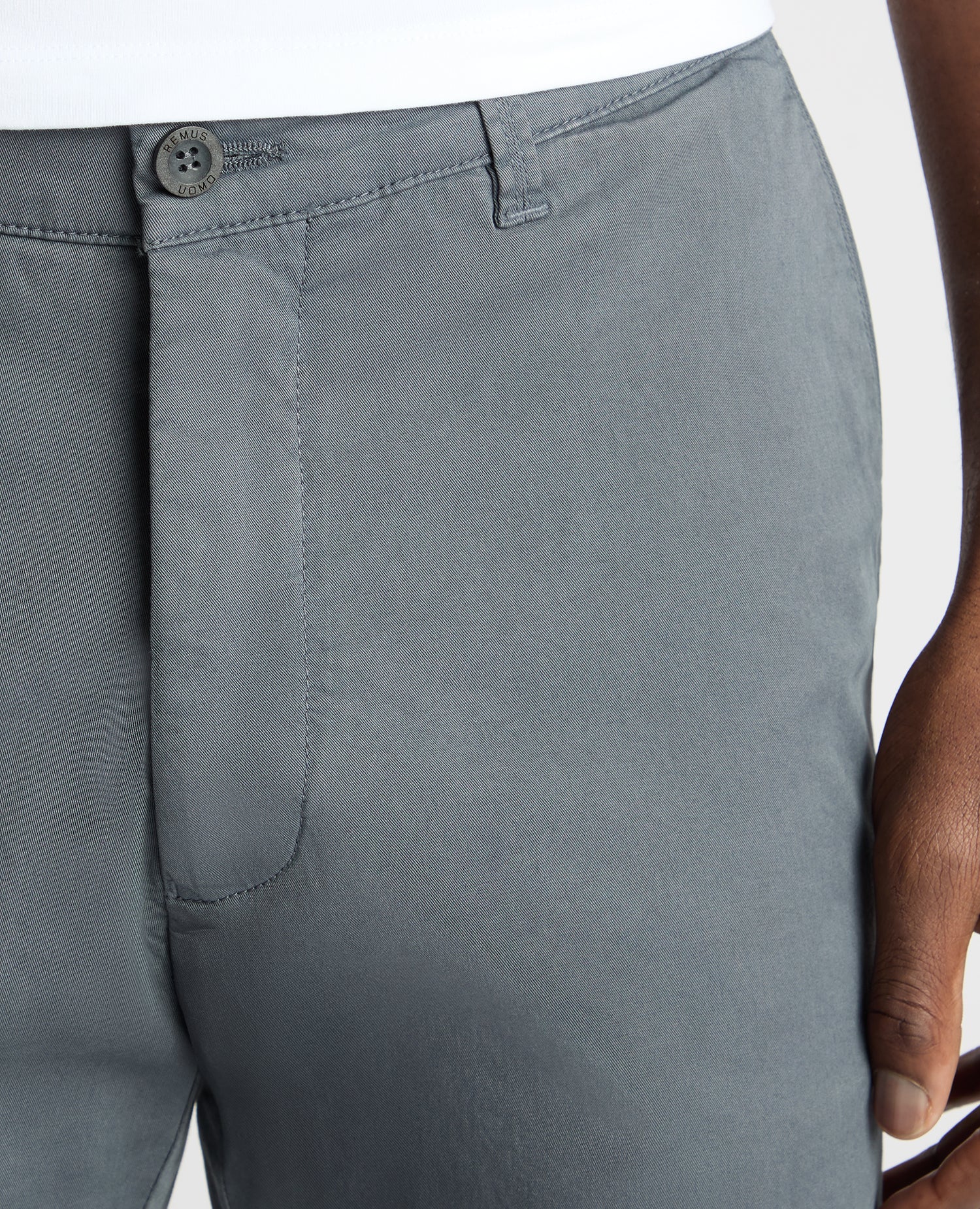 Close-up of gray pants with a button on a white background