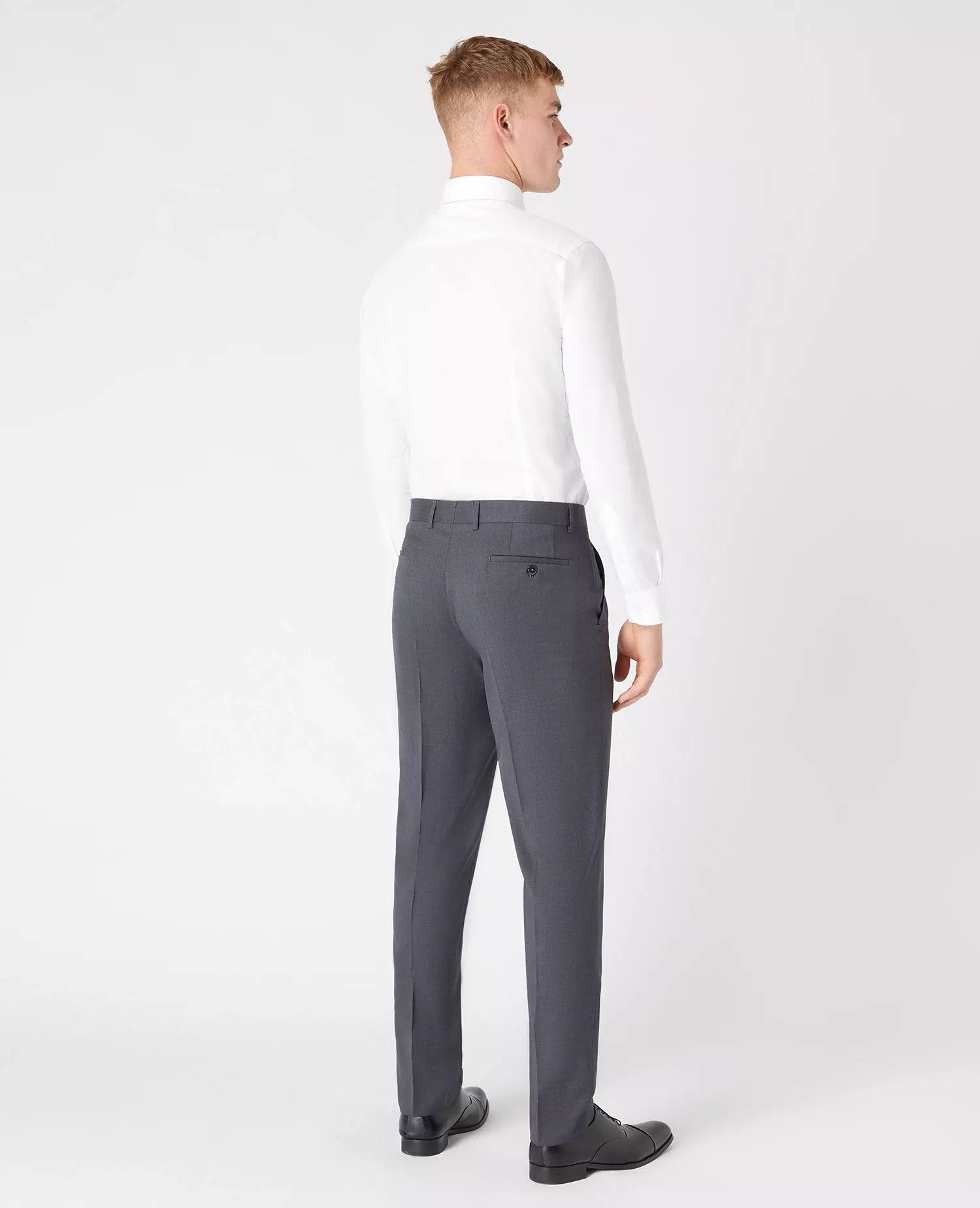 Man wearing a white shirt and gray pants on a white background