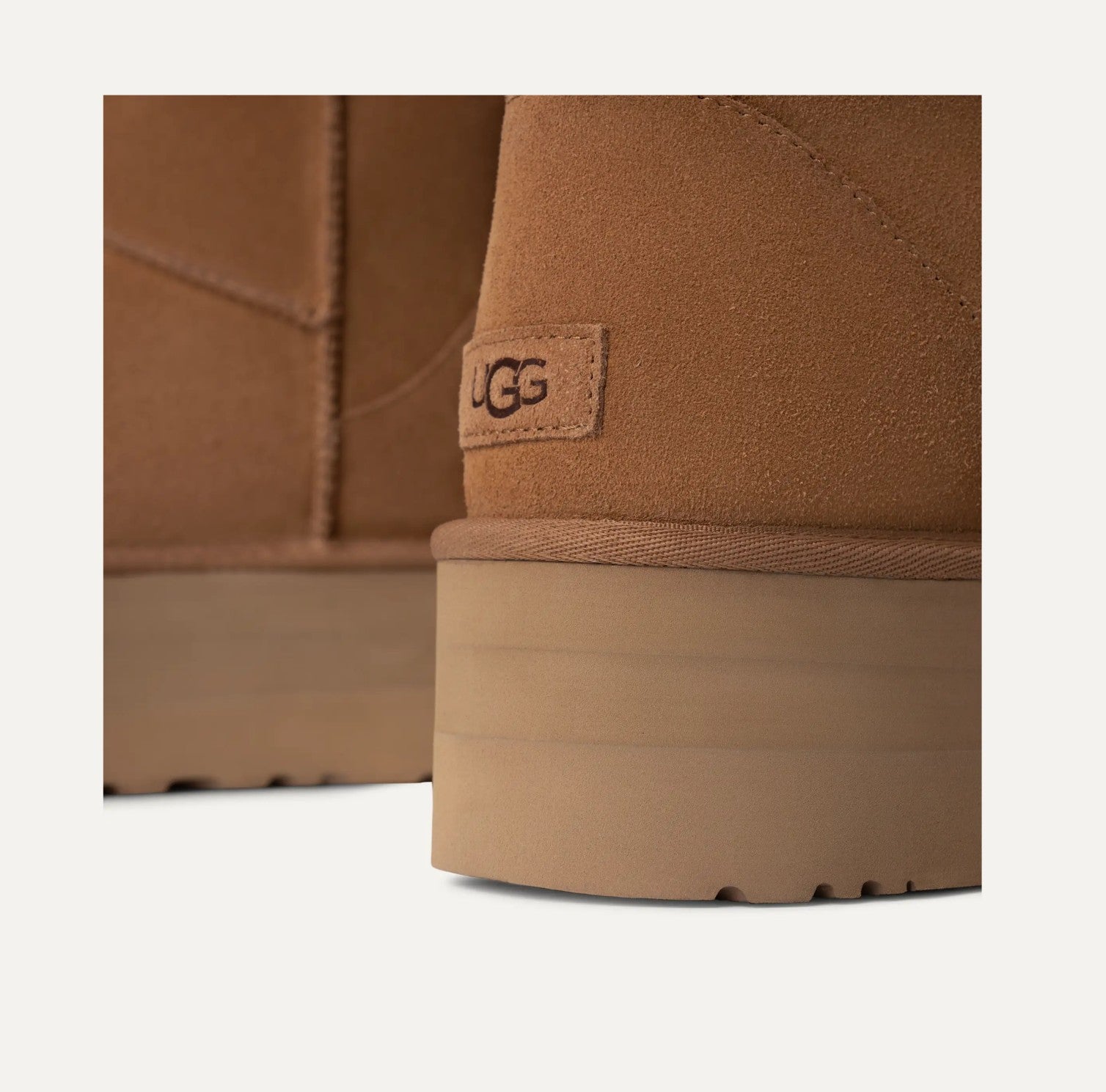 Close-up of a brown UGG boot with a visible brand logo on a white background
