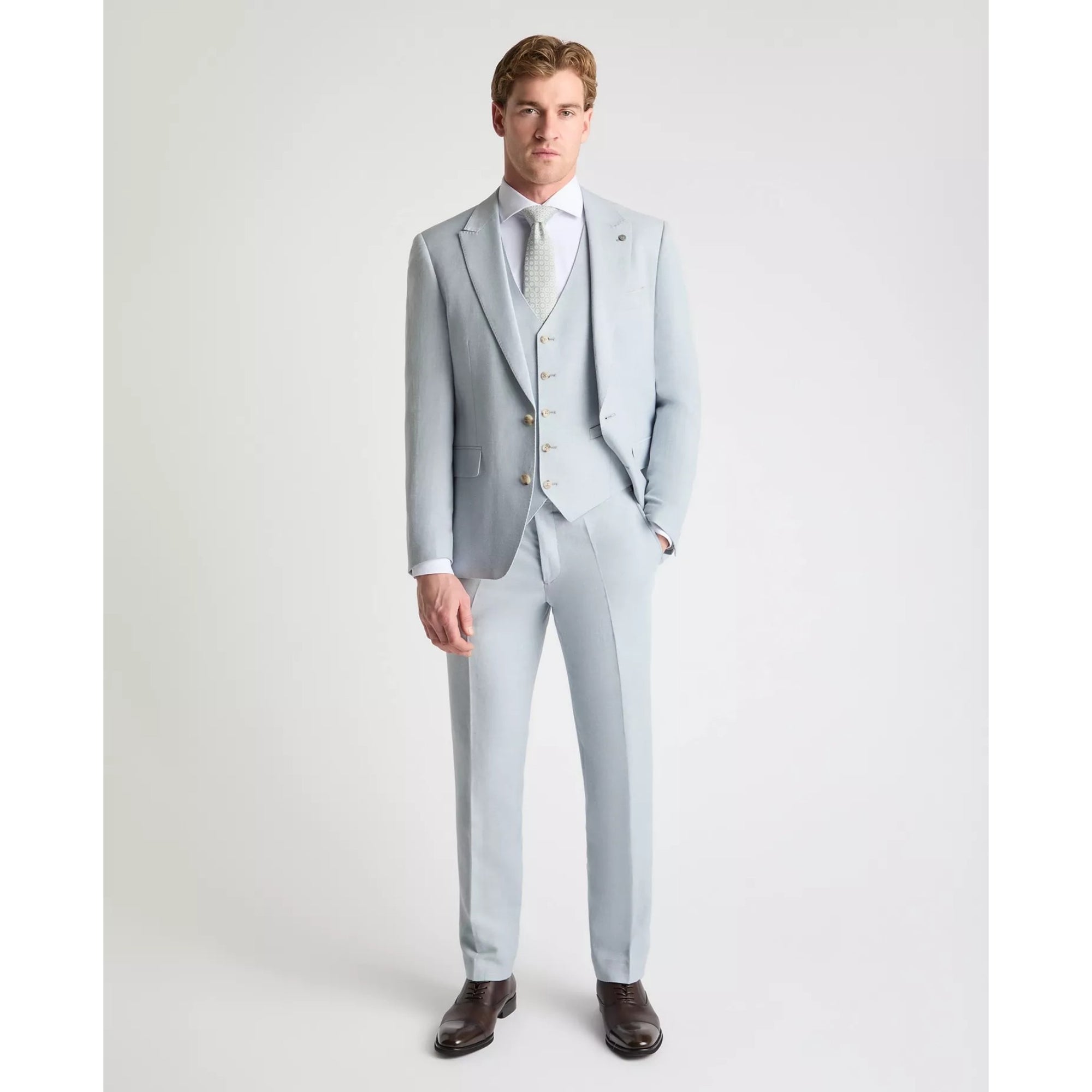 Man wearing a sky blue suit with a white shirt on a plain background
