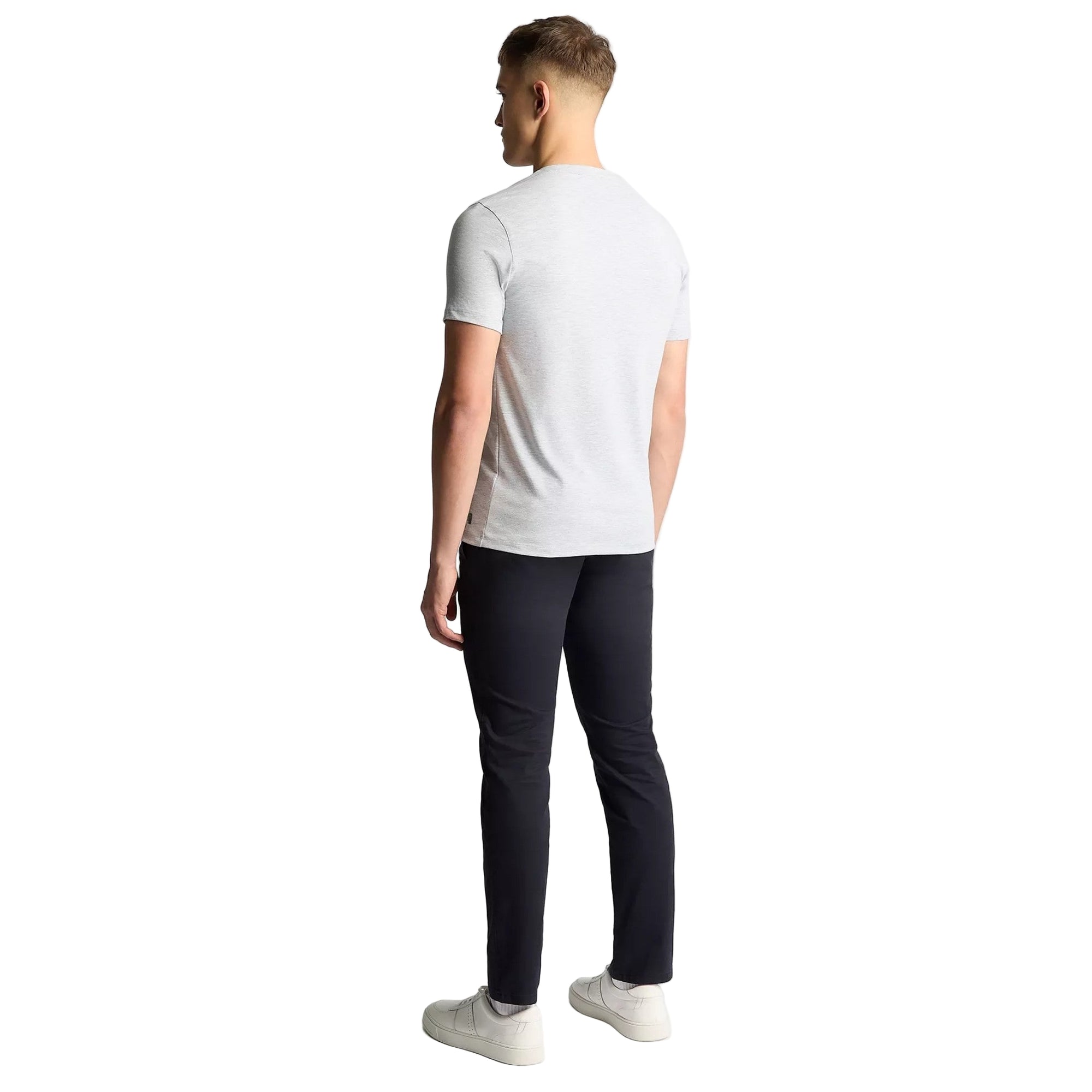 Man wearing a white t-shirt and black pants on a light gray background