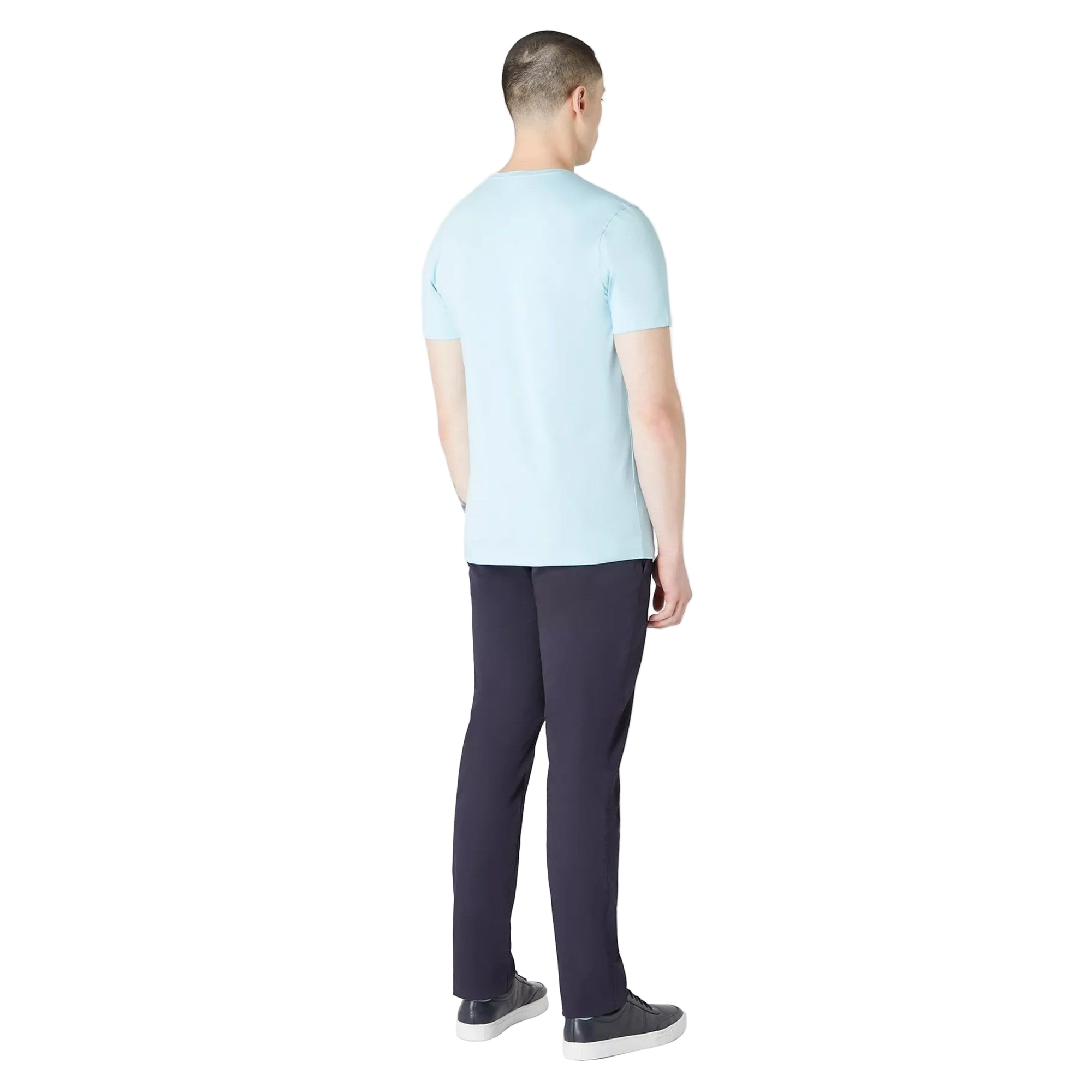 Man wearing a light blue t-shirt and dark pants on a white background