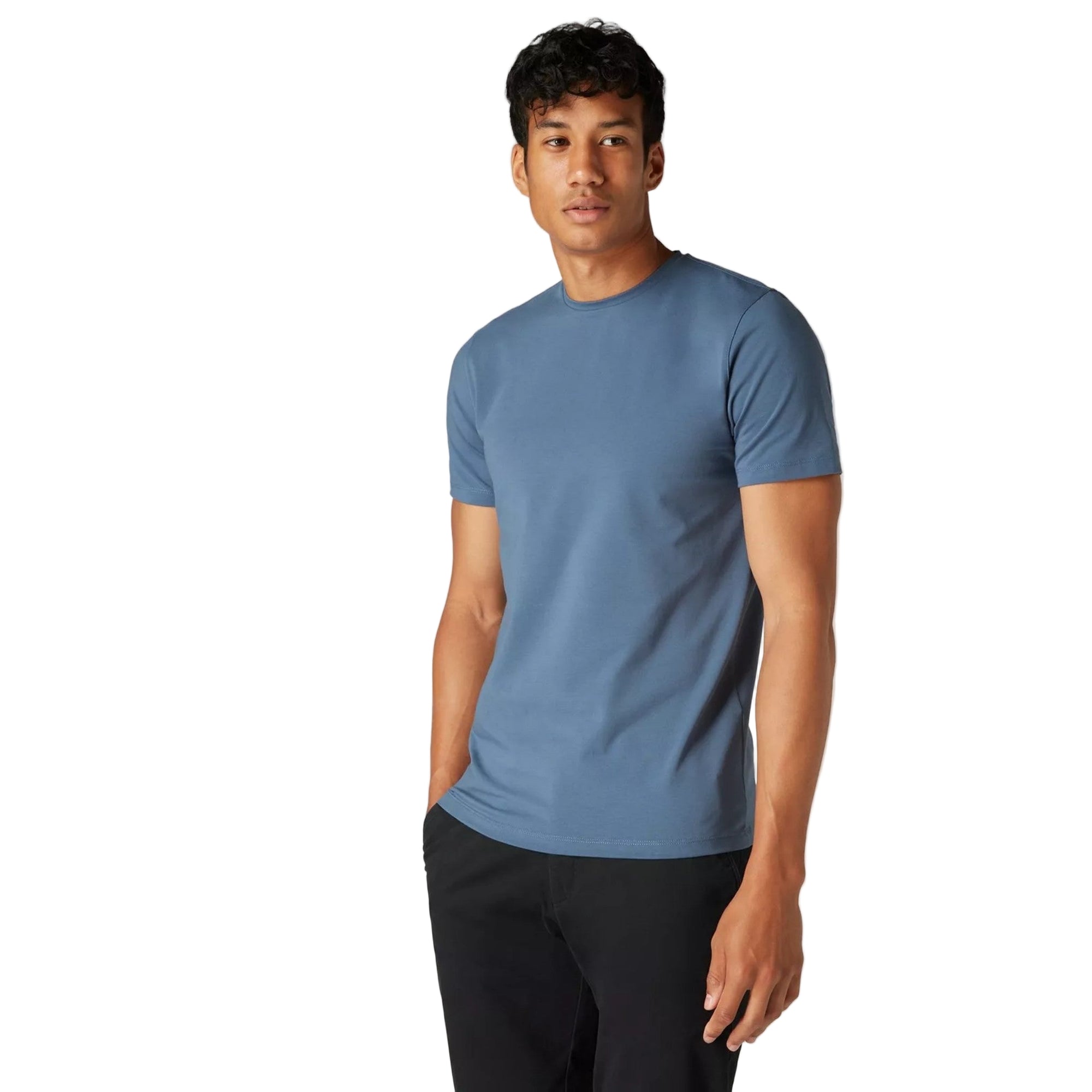 Man wearing a blue t-shirt and black pants on a light gray background
