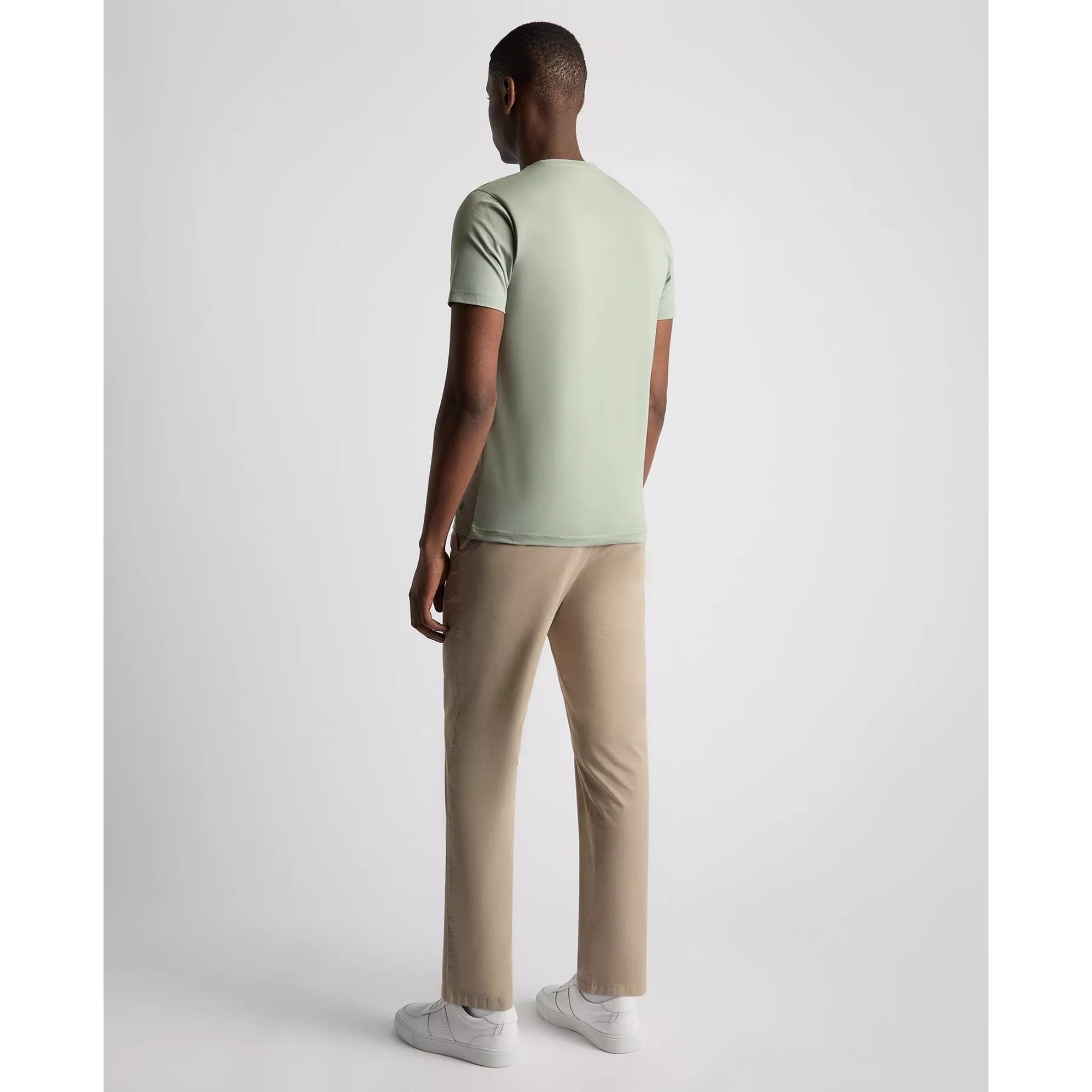 Person wearing a light green t-shirt and beige pants on a white background