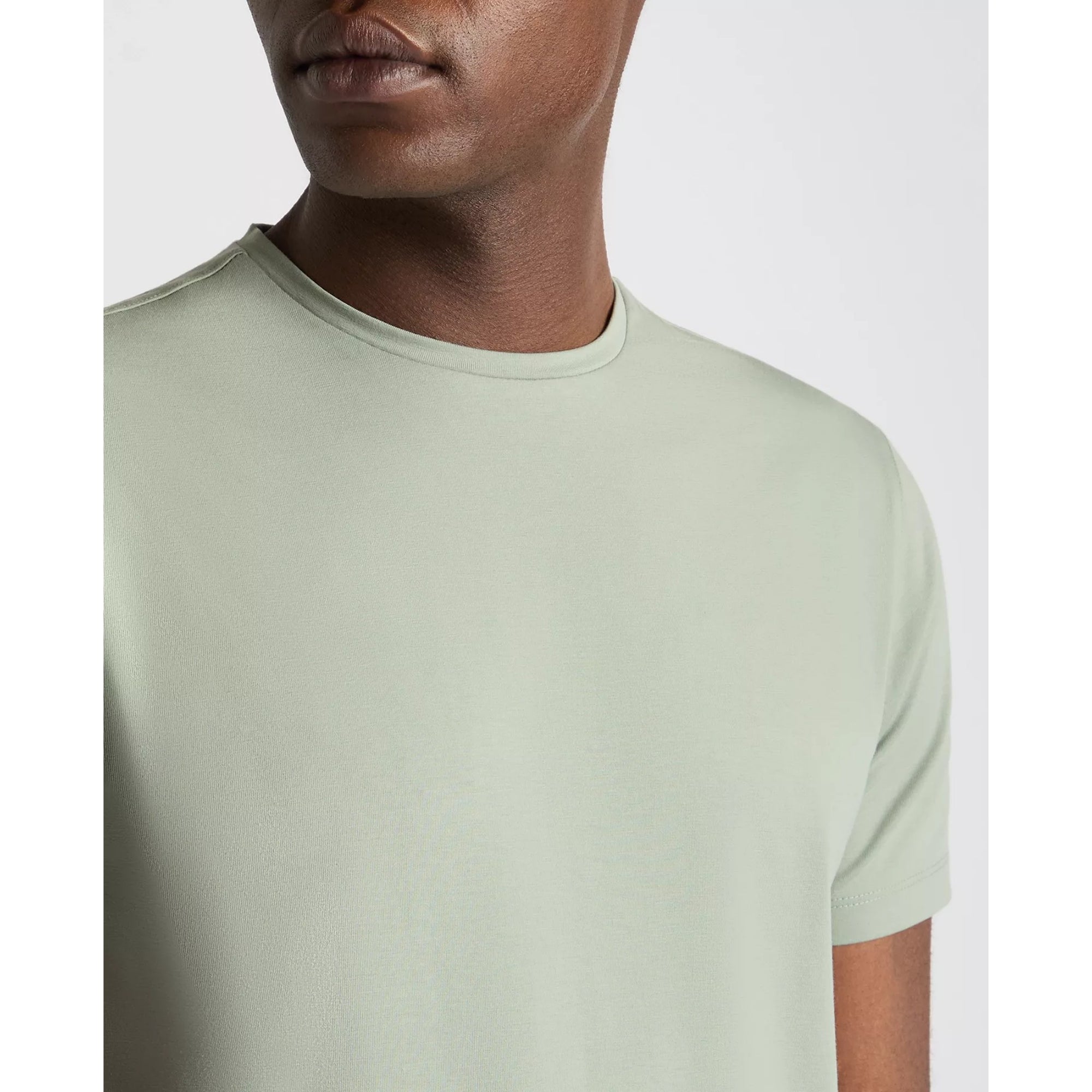 Person wearing a light green t-shirt on a white background