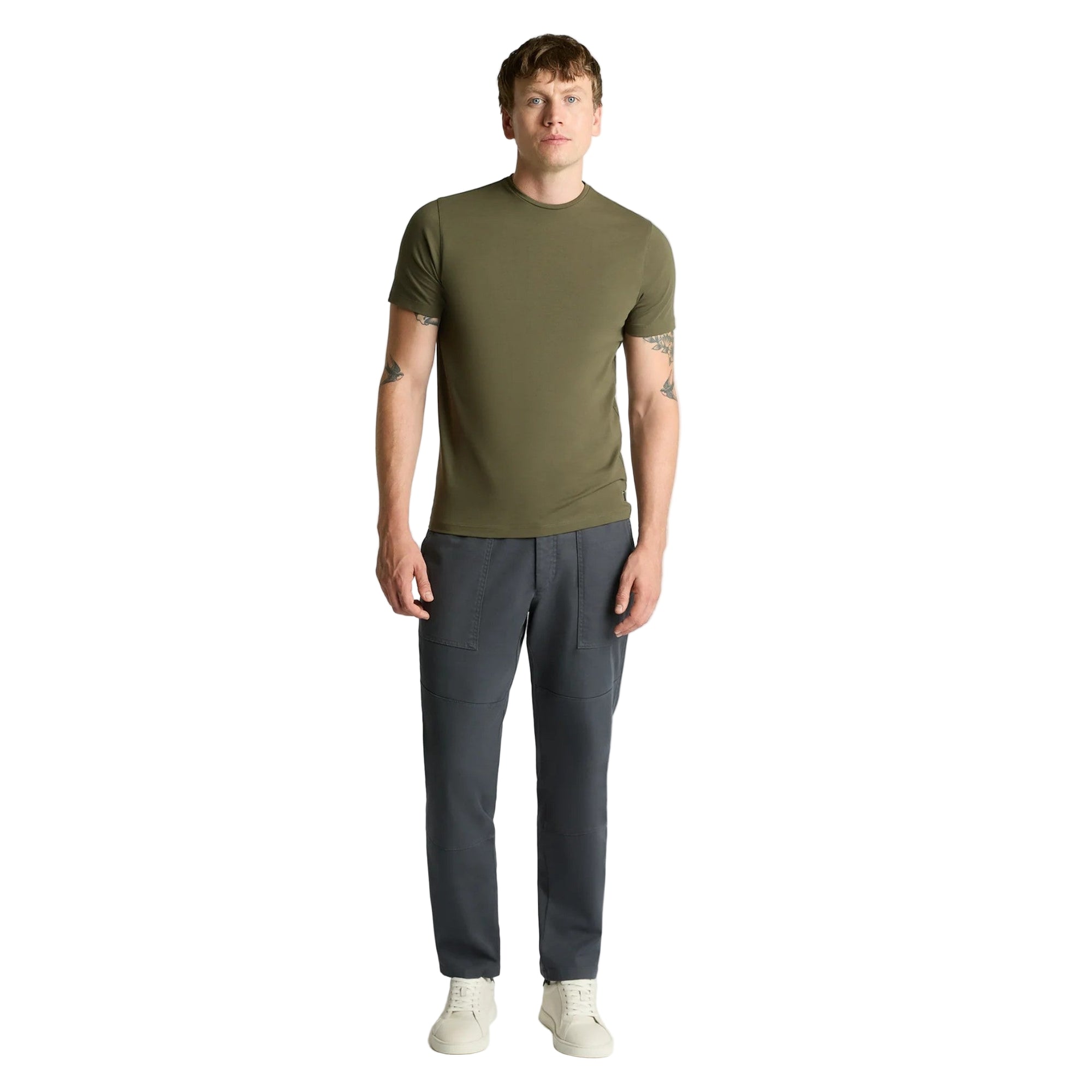Man wearing an olive green t-shirt and dark gray pants on a white background