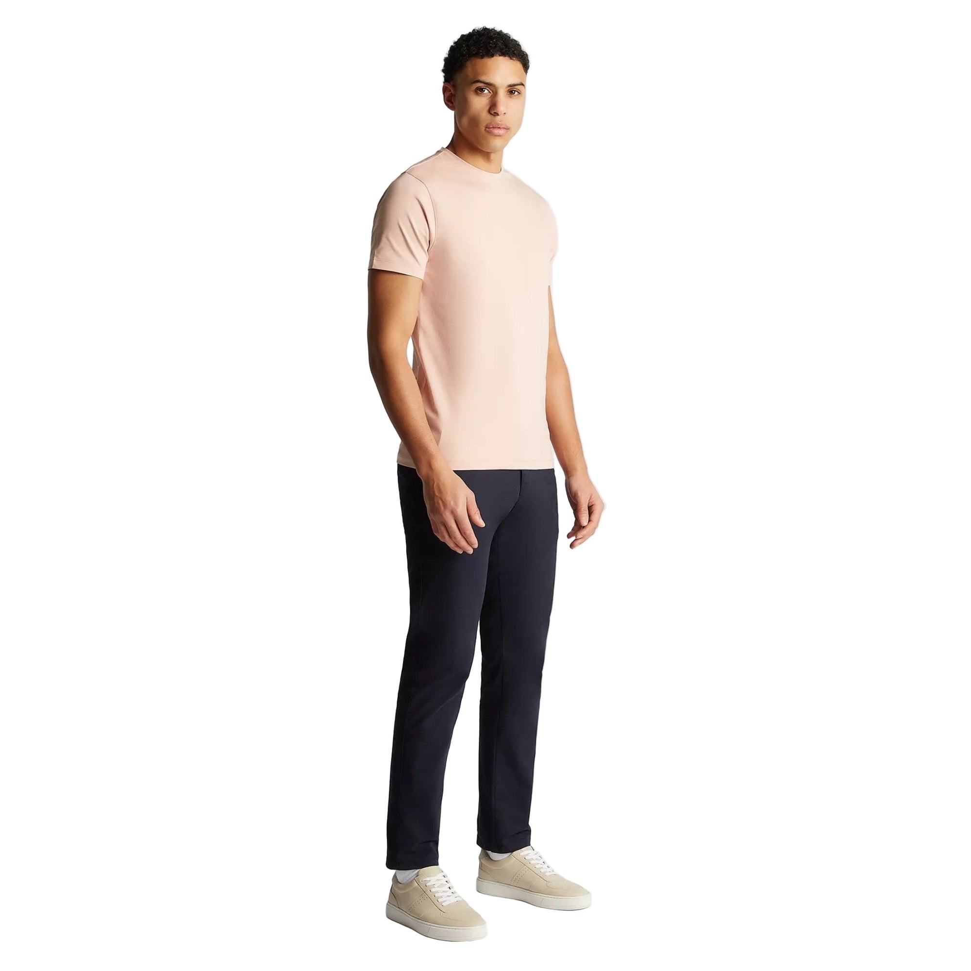 Man wearing a light pink t-shirt and black pants on a white background
