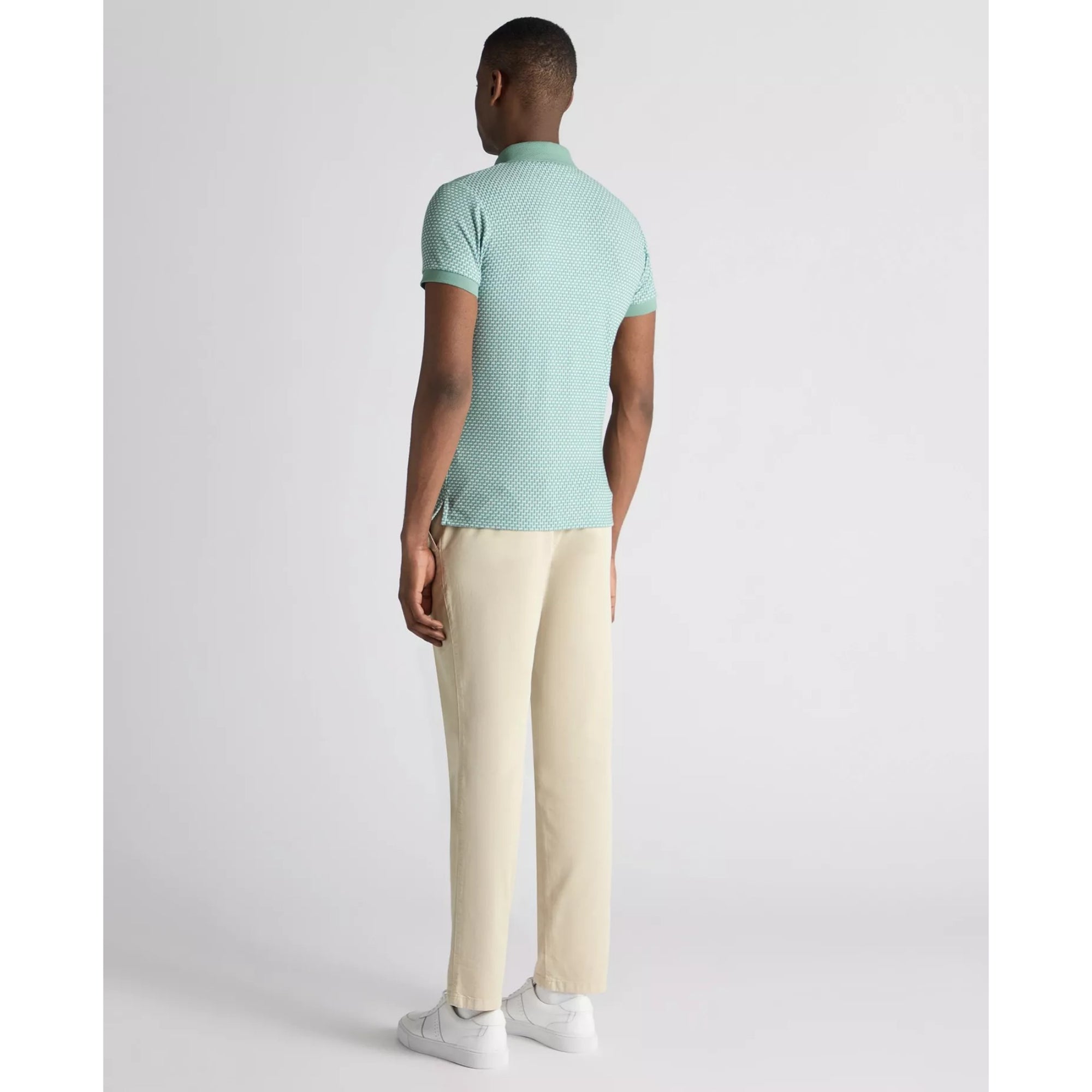 Man wearing a light green polo shirt and beige pants on a white background
