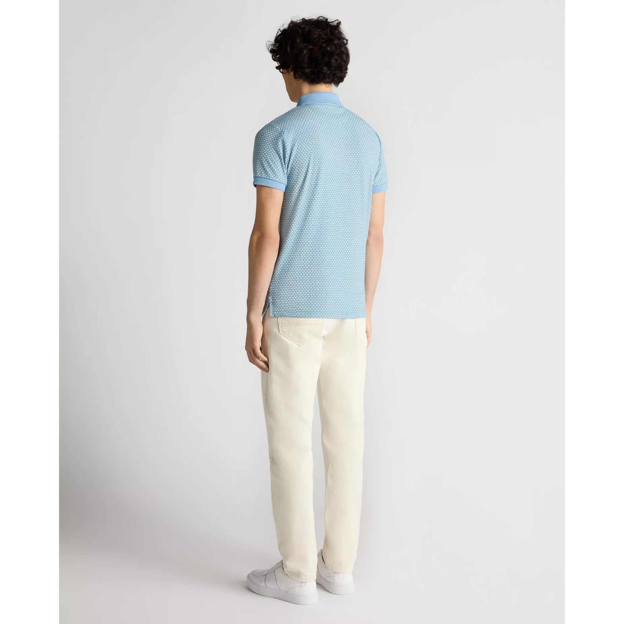 Person wearing a light blue patterned polo shirt and beige pants on a white background