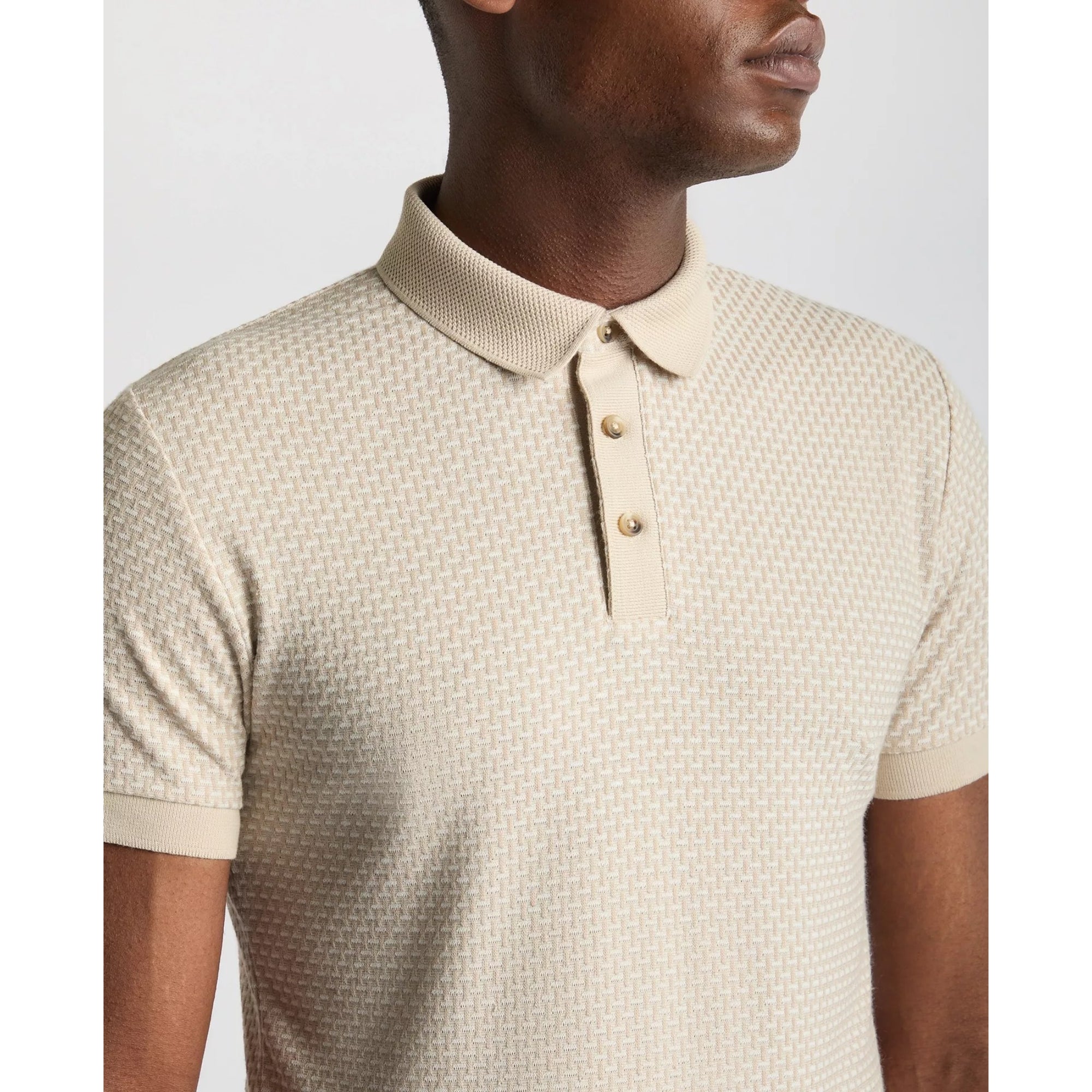 Man wearing a beige patterned polo shirt against a plain background