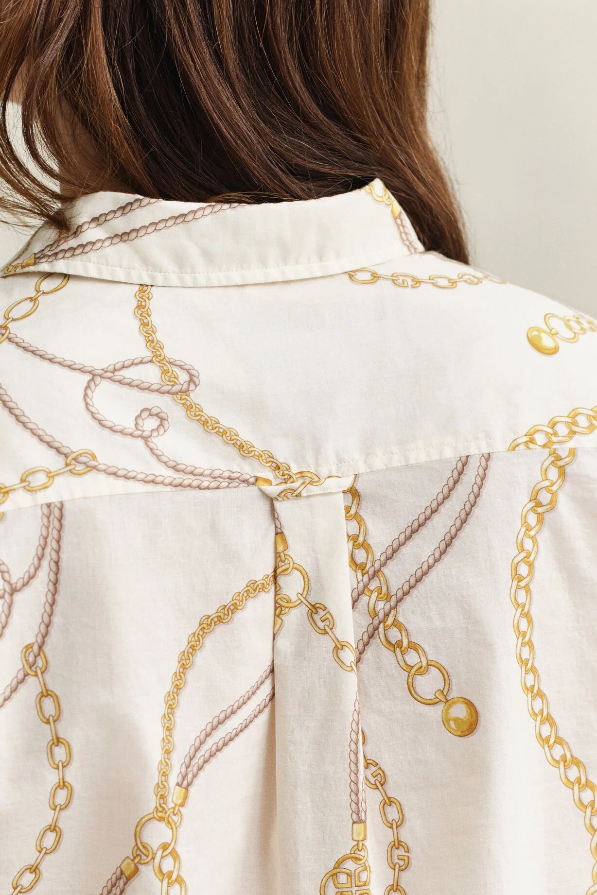 Close-up of a white shirt with gold chain pattern