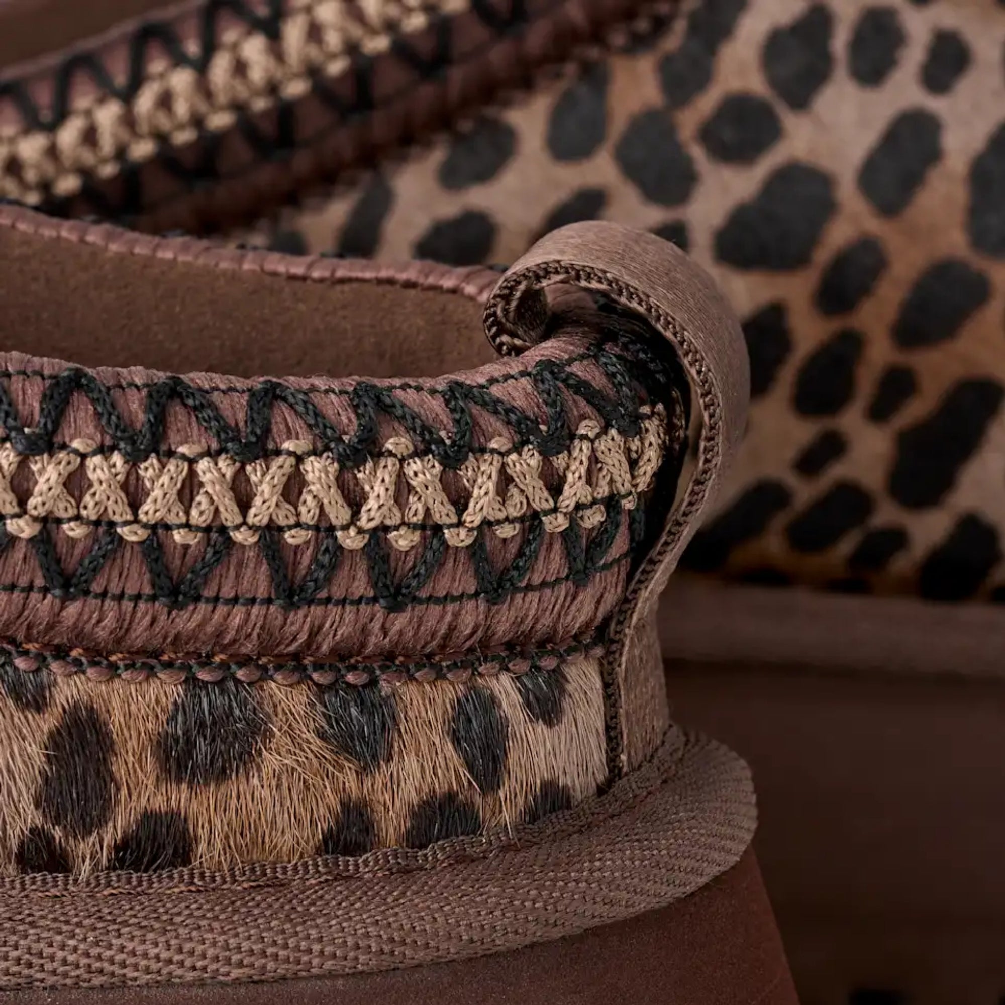 Close-up of a brown shoe with leopard print pattern and intricate lace design.