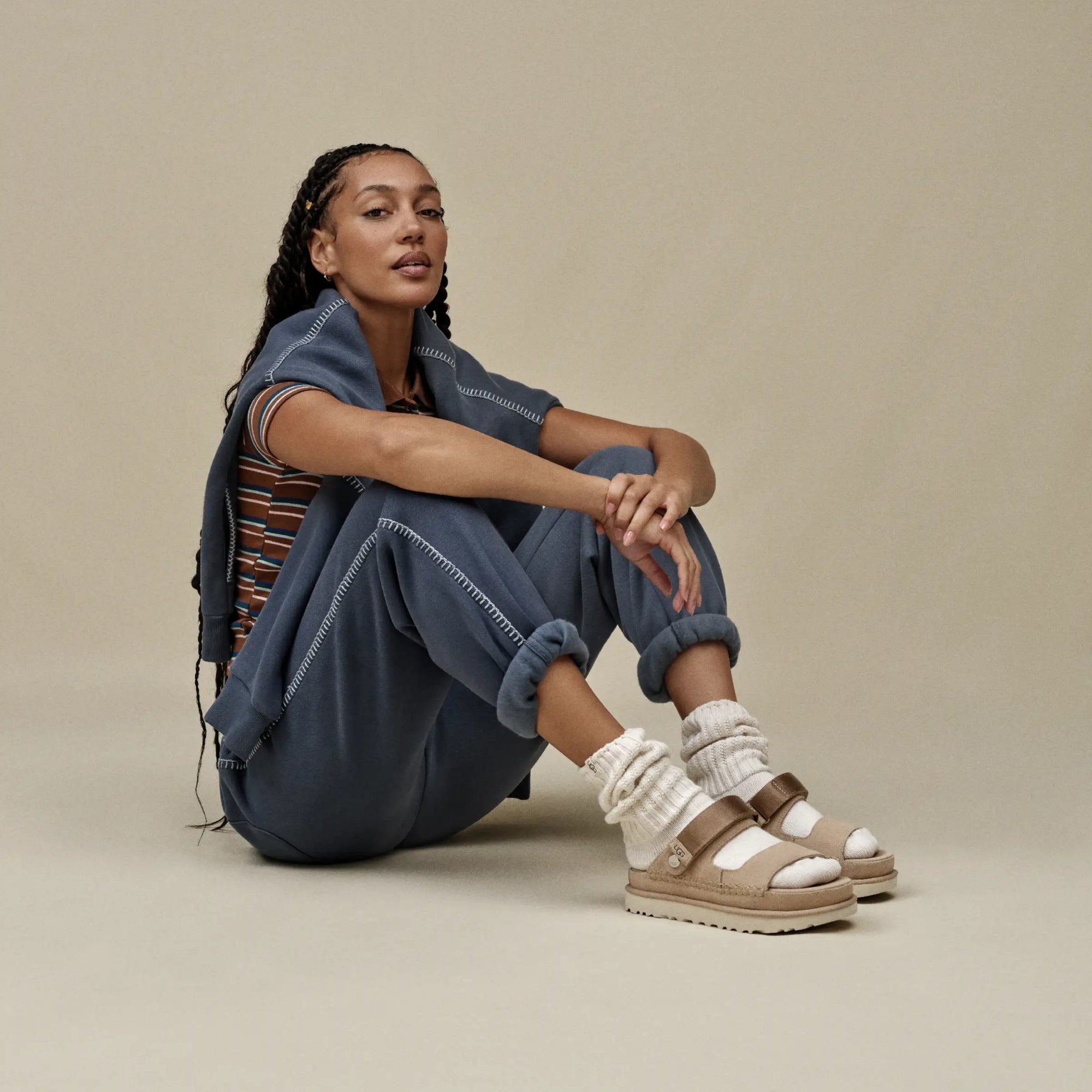 A pair of UGG Goldenstar Glide sandals in sand color with an adjustable heel strap and a low heel.