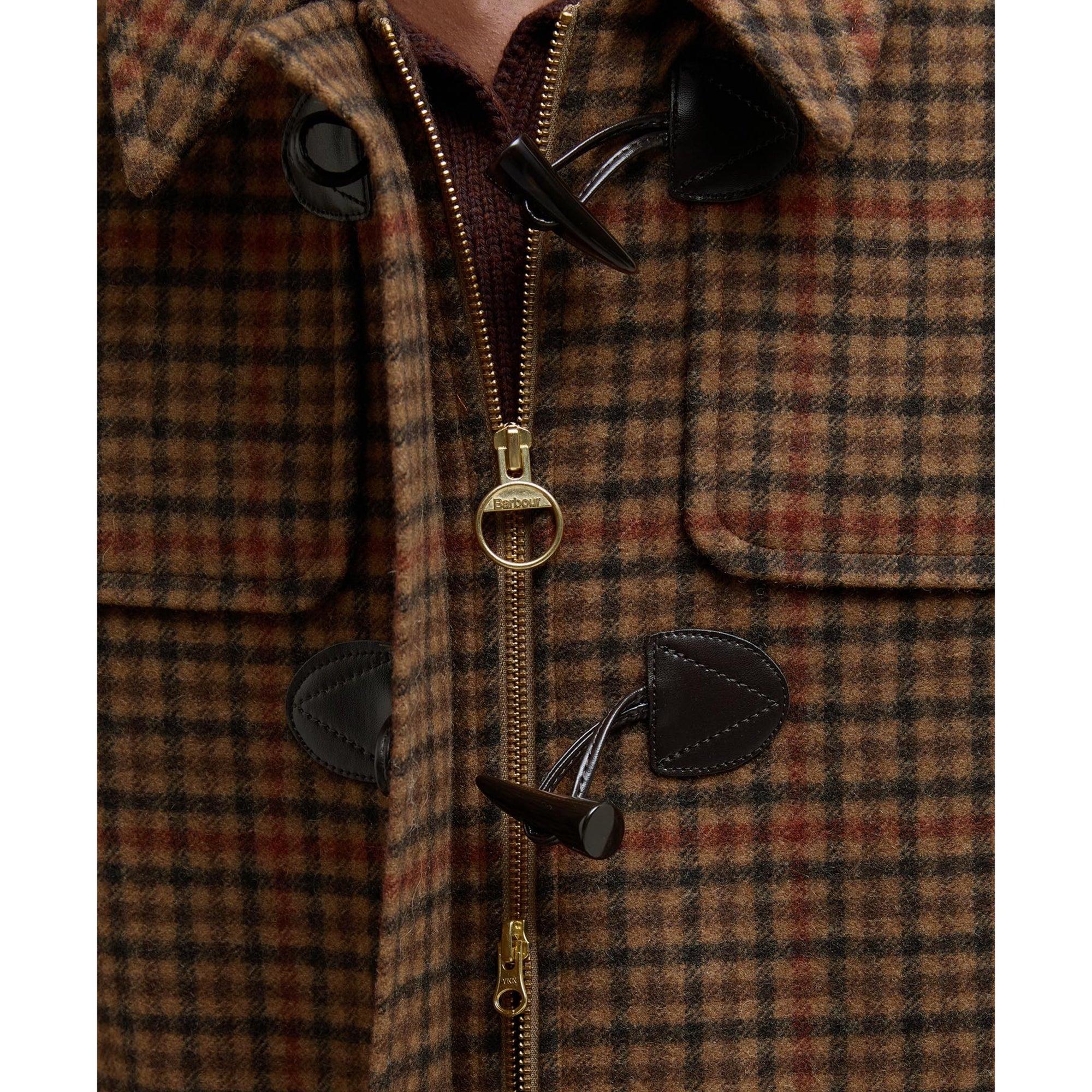 Close-up of a plaid coat with a zipper and buttons on a white background