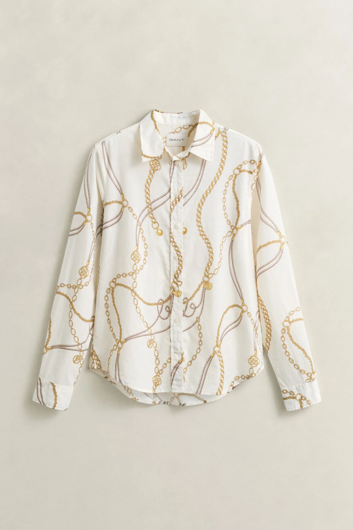 White blouse with gold chain pattern on a beige background