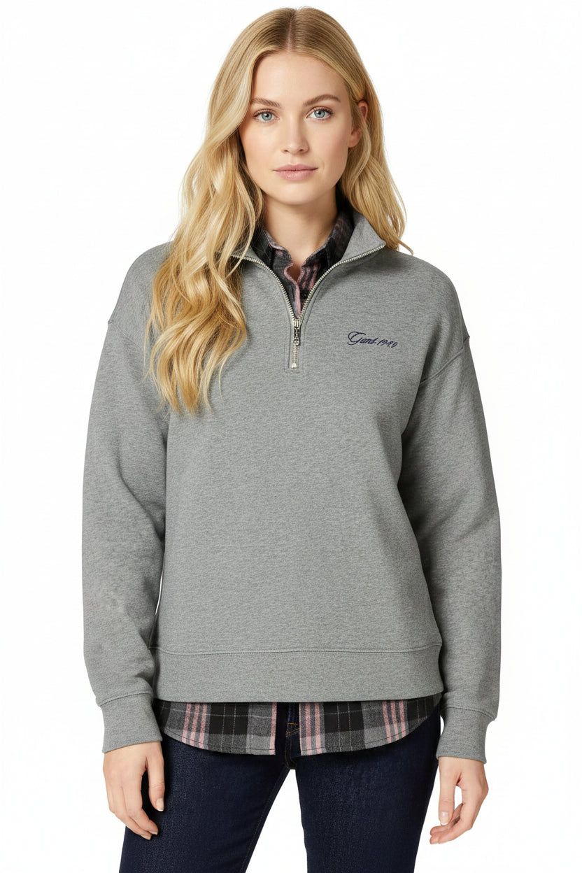 Woman wearing a gray quarter-zip sweatshirt with a GANT logo on a white background