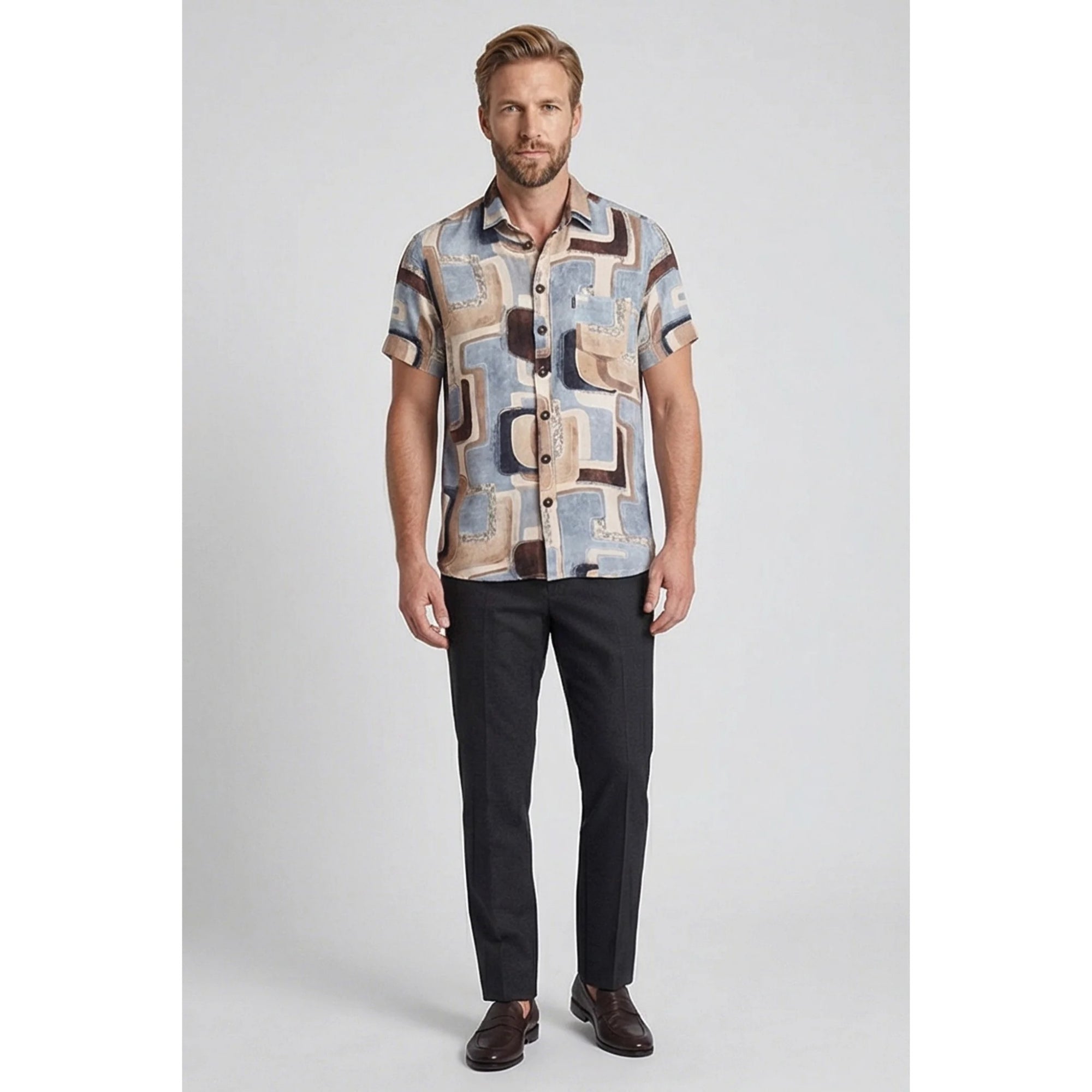 Man wearing a patterned shirt and dark pants on a gray background