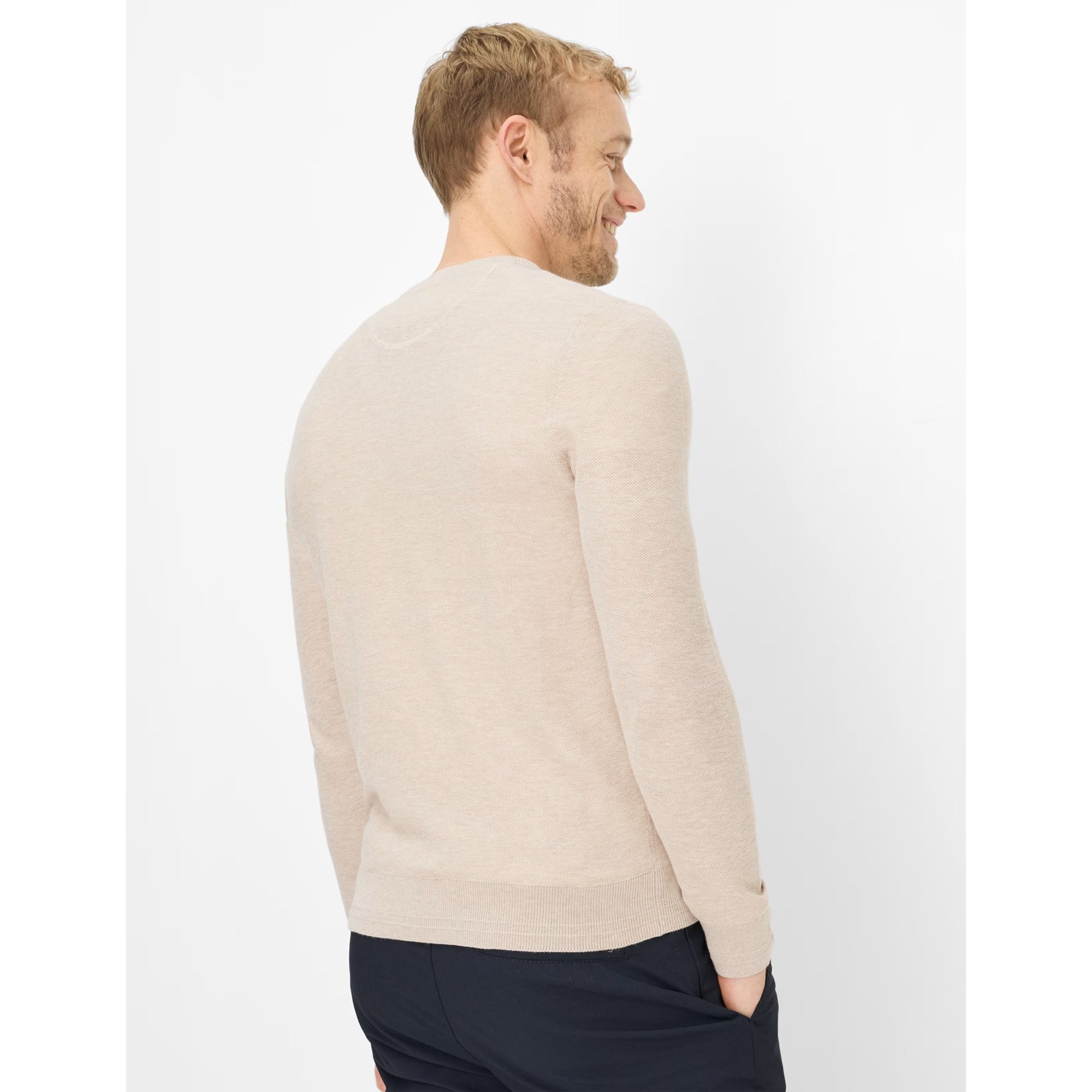 Man wearing a beige sweater on a white background