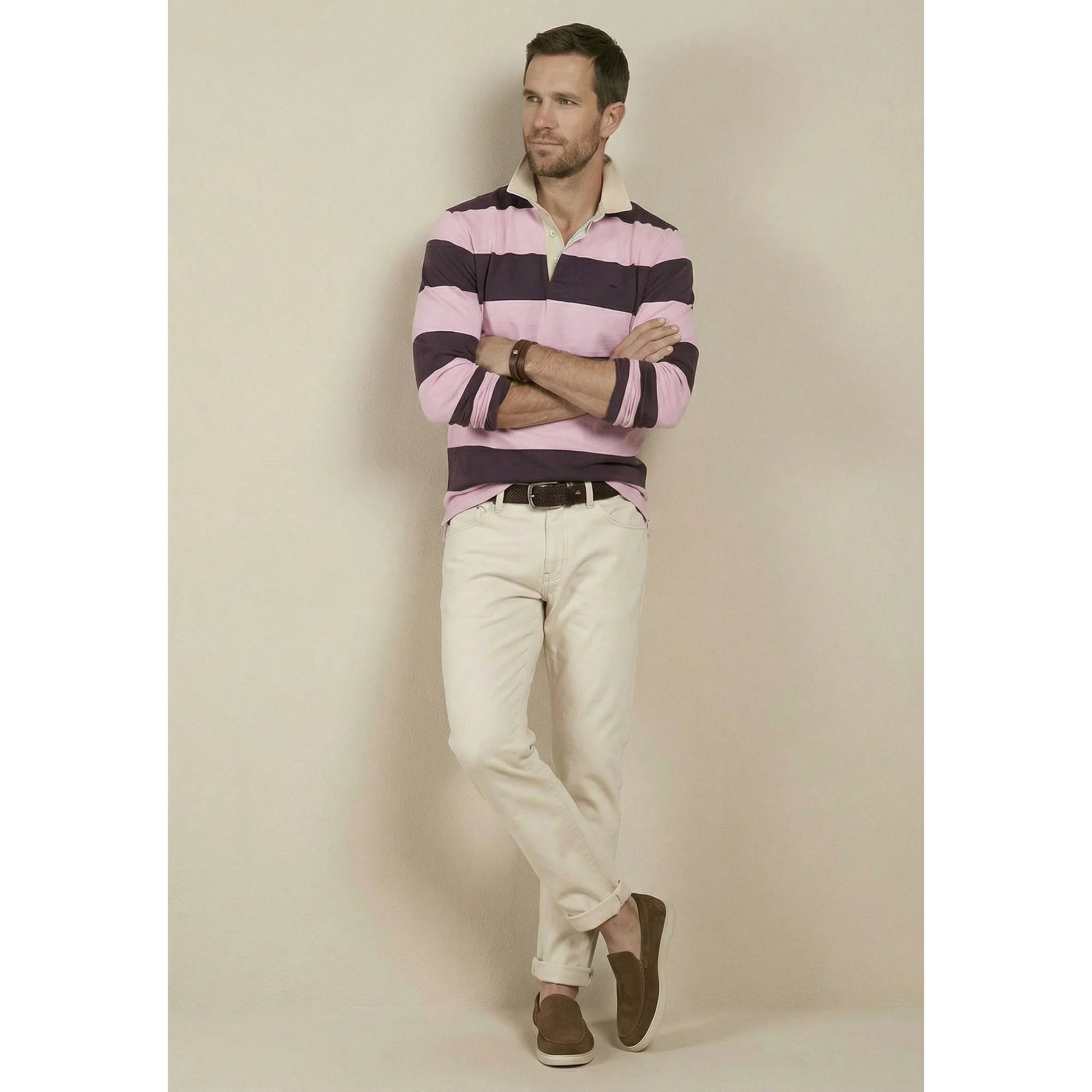 Man wearing a striped shirt and beige pants against a plain background