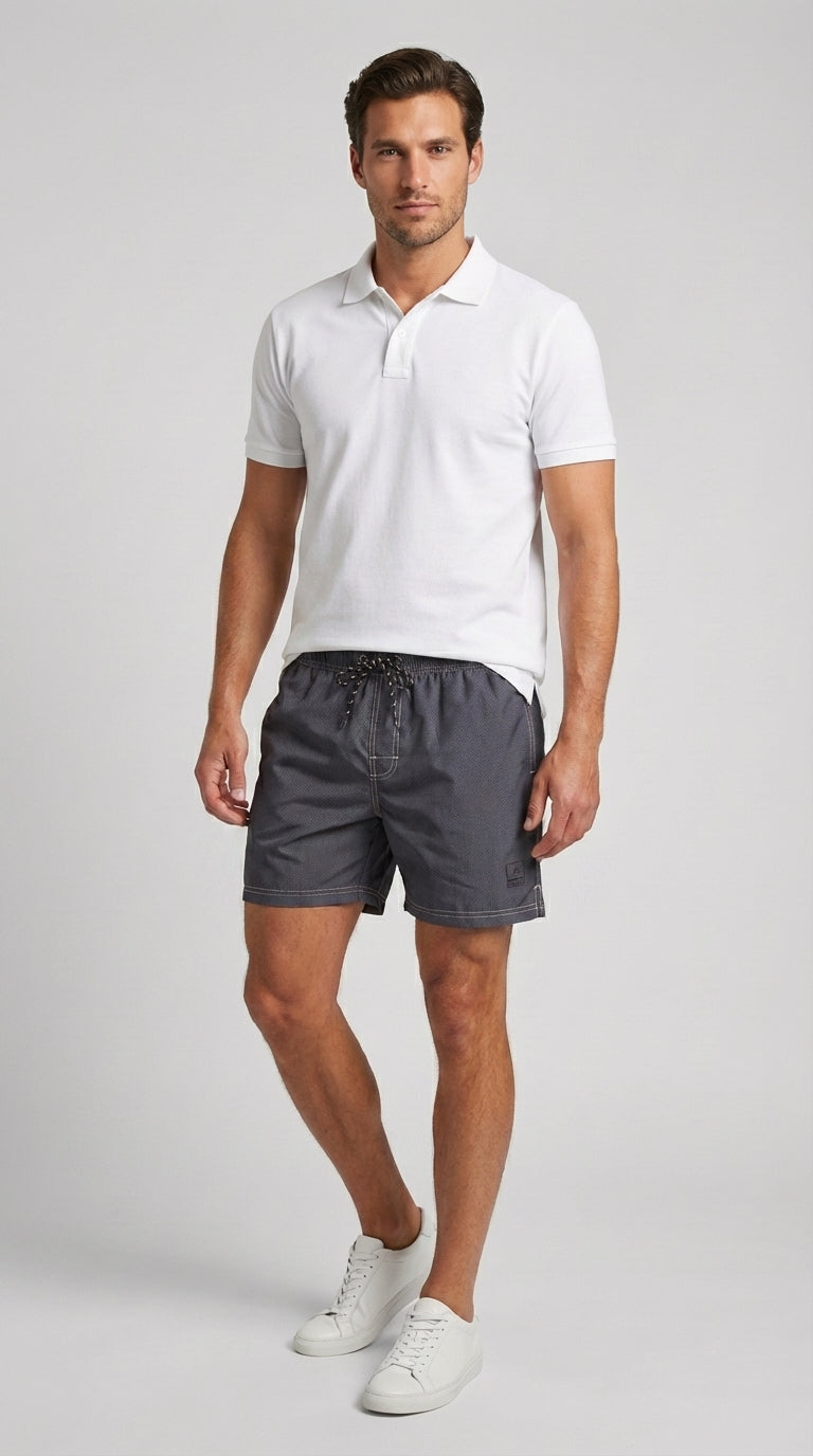 Man wearing a white polo shirt and gray shorts on a light gray background