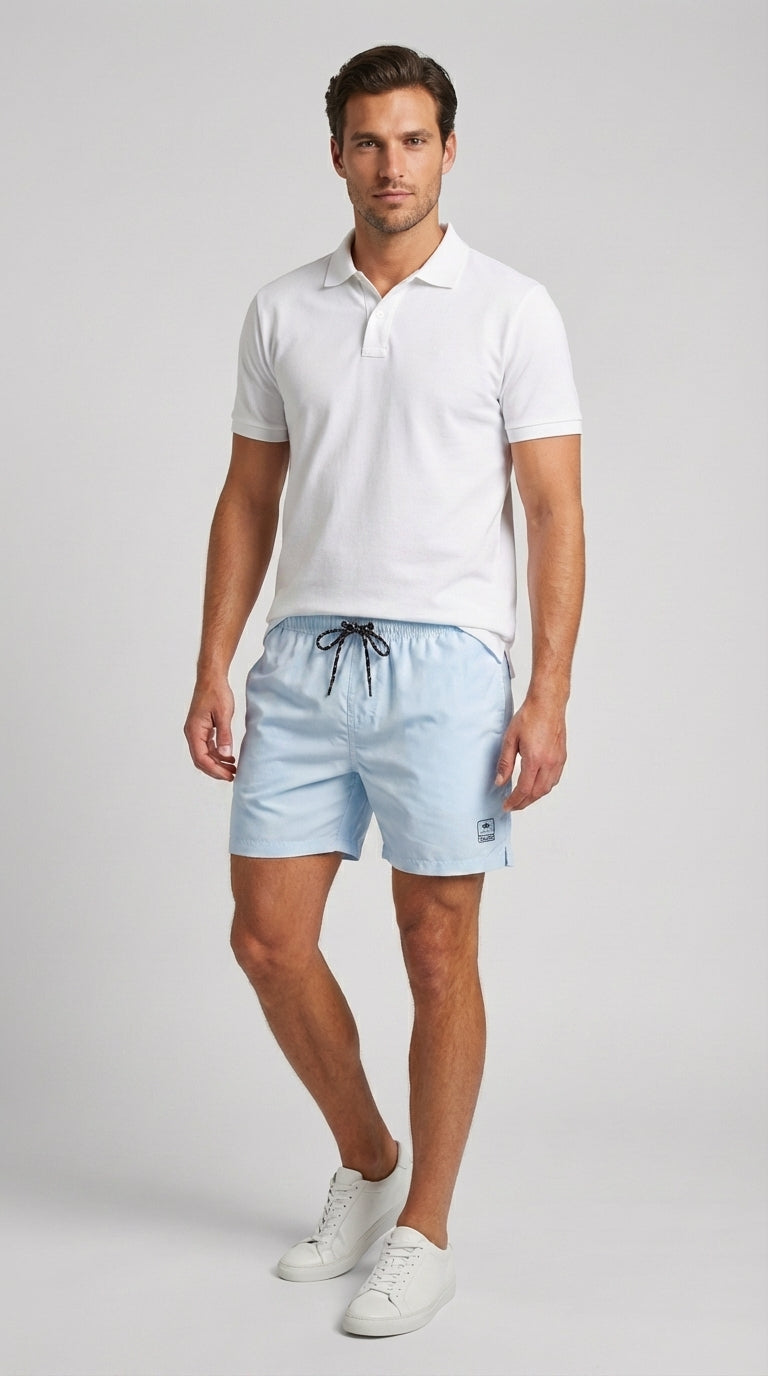 Man wearing a white polo shirt and light blue shorts on a gray background