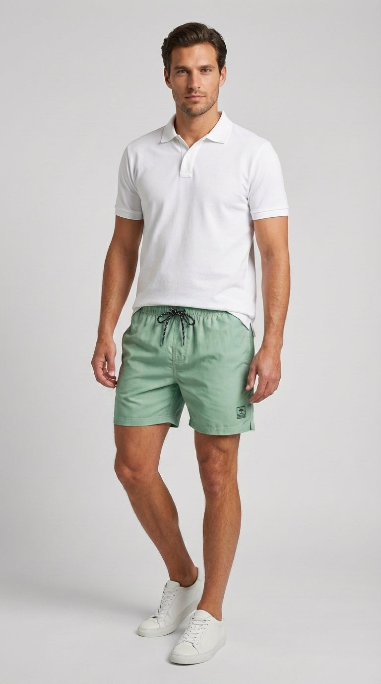 Man wearing a white polo shirt and green shorts on a light gray background
